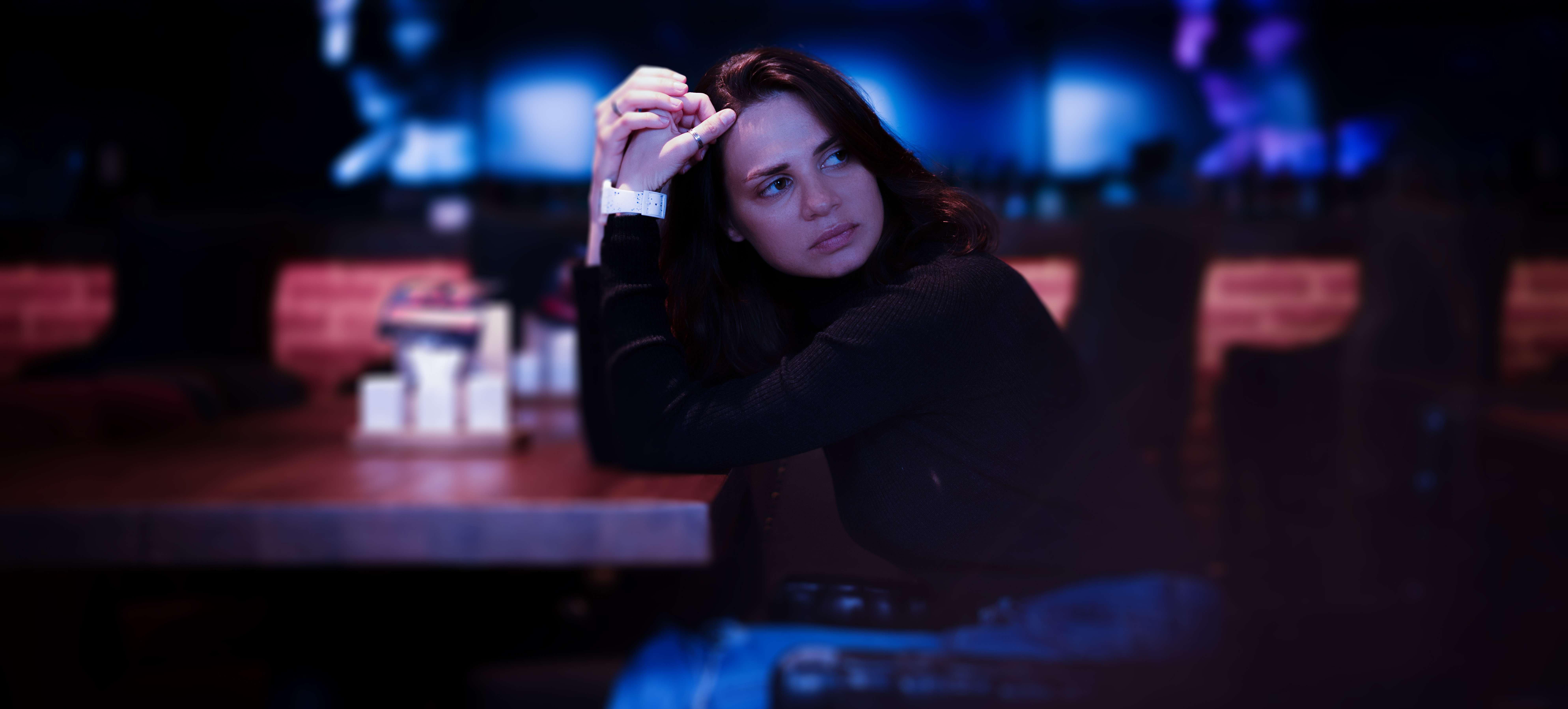 Sad serious young woman sitting in a night restaurant alone. | Source: Shutterstock