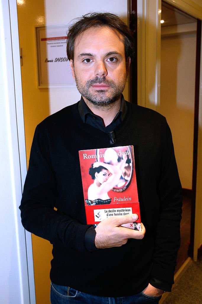 Romain Sardou présente ses livres “Fraulein France” lors de l'émission de télévision française “Vivement Dimanche'' au Pavillon Gabriel le 12 novembre 2014 à Paris. | Photo : Getty Images Romain Sardou présente ses livres “Fraulein France” lors de l'émission de télévision française “Vivement Dimanche'' au Pavillon Gabriel le 12 novembre 2014 à Paris. | Photo : Getty Images