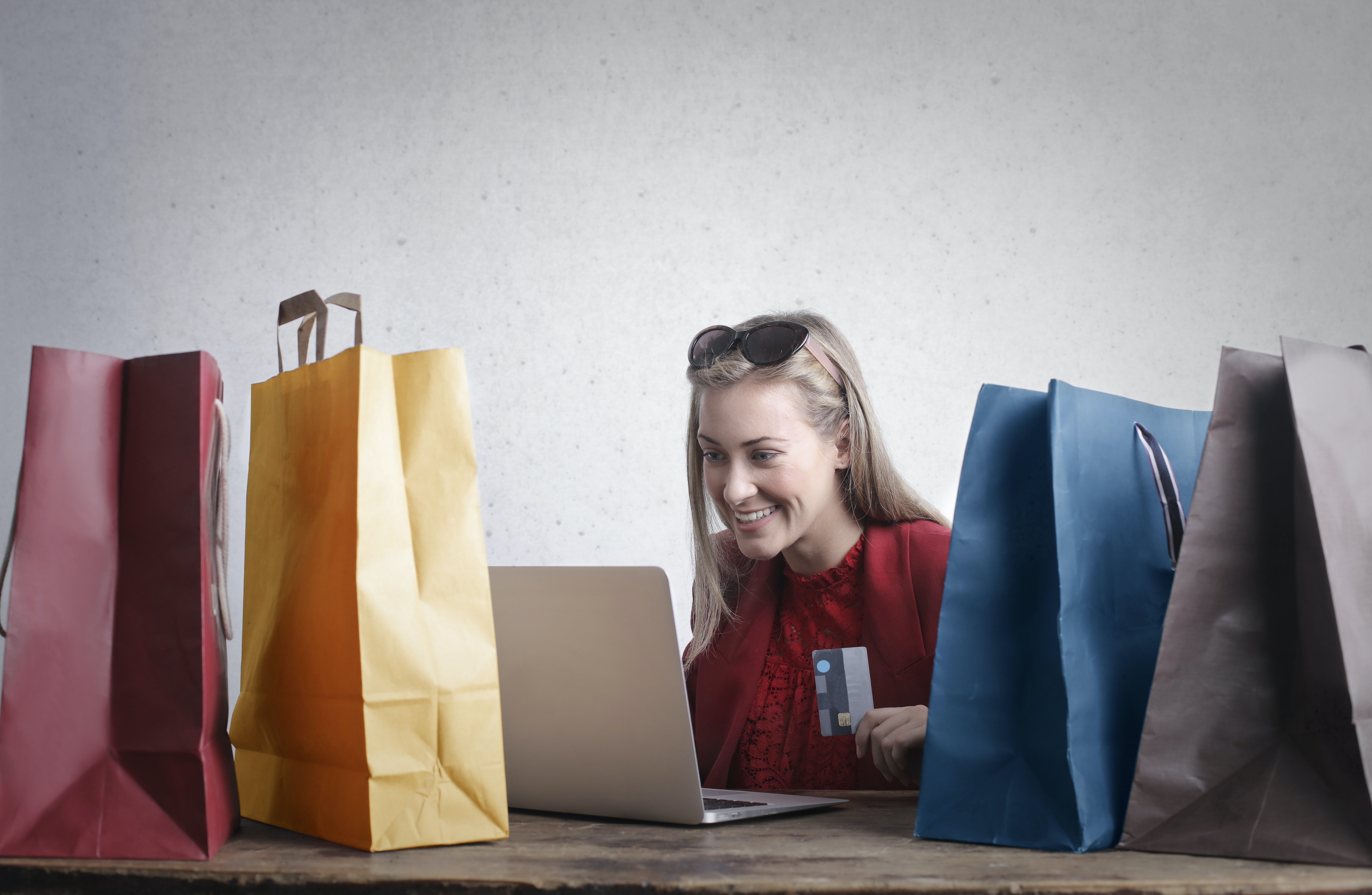 A happy woman shopping online at home posing alongside shopping bags | Source: Pexels 