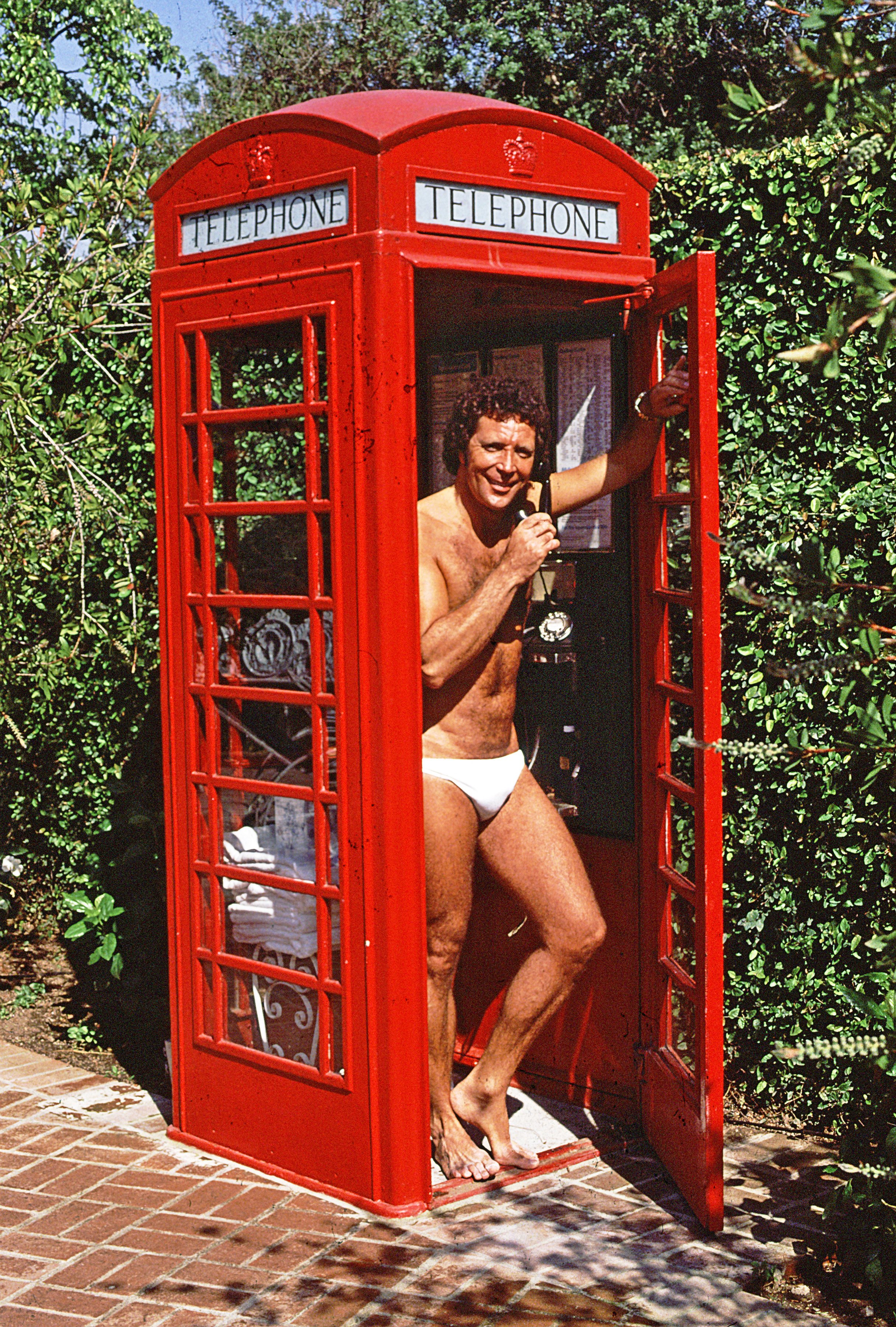 Tom Jones posing for a picture inside his red phone box | Source: Getty Images