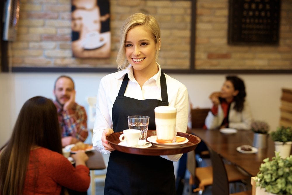 Waitress smiling while holding tray with coffee.|Source: Shutterstock