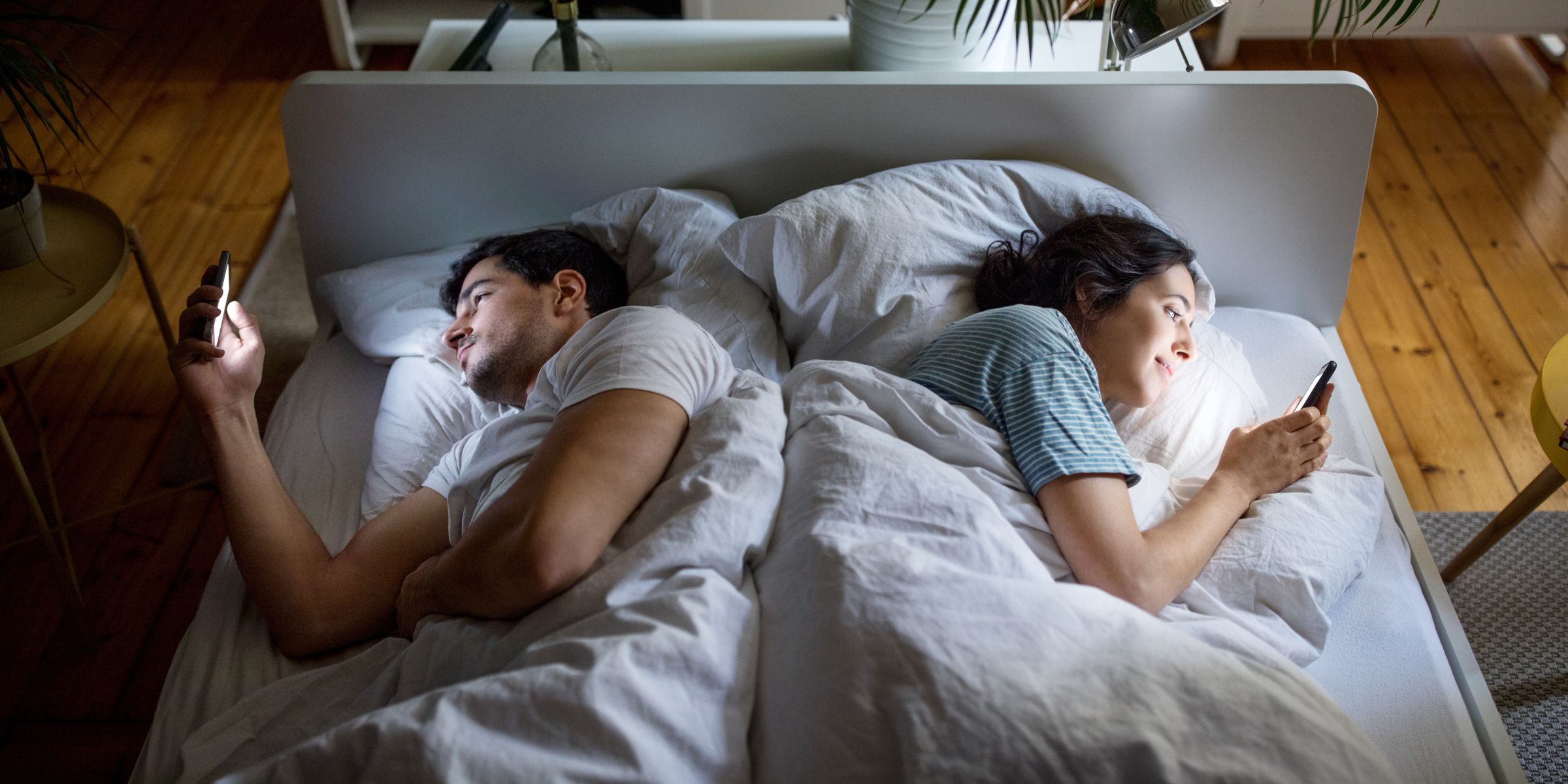 A couple using mobile phones in bed | Source: Getty Images