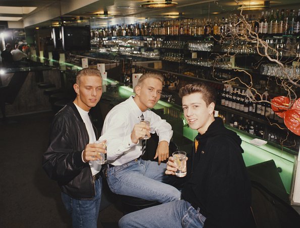 Three young men having a drink in a bar | Photo: Getty Images