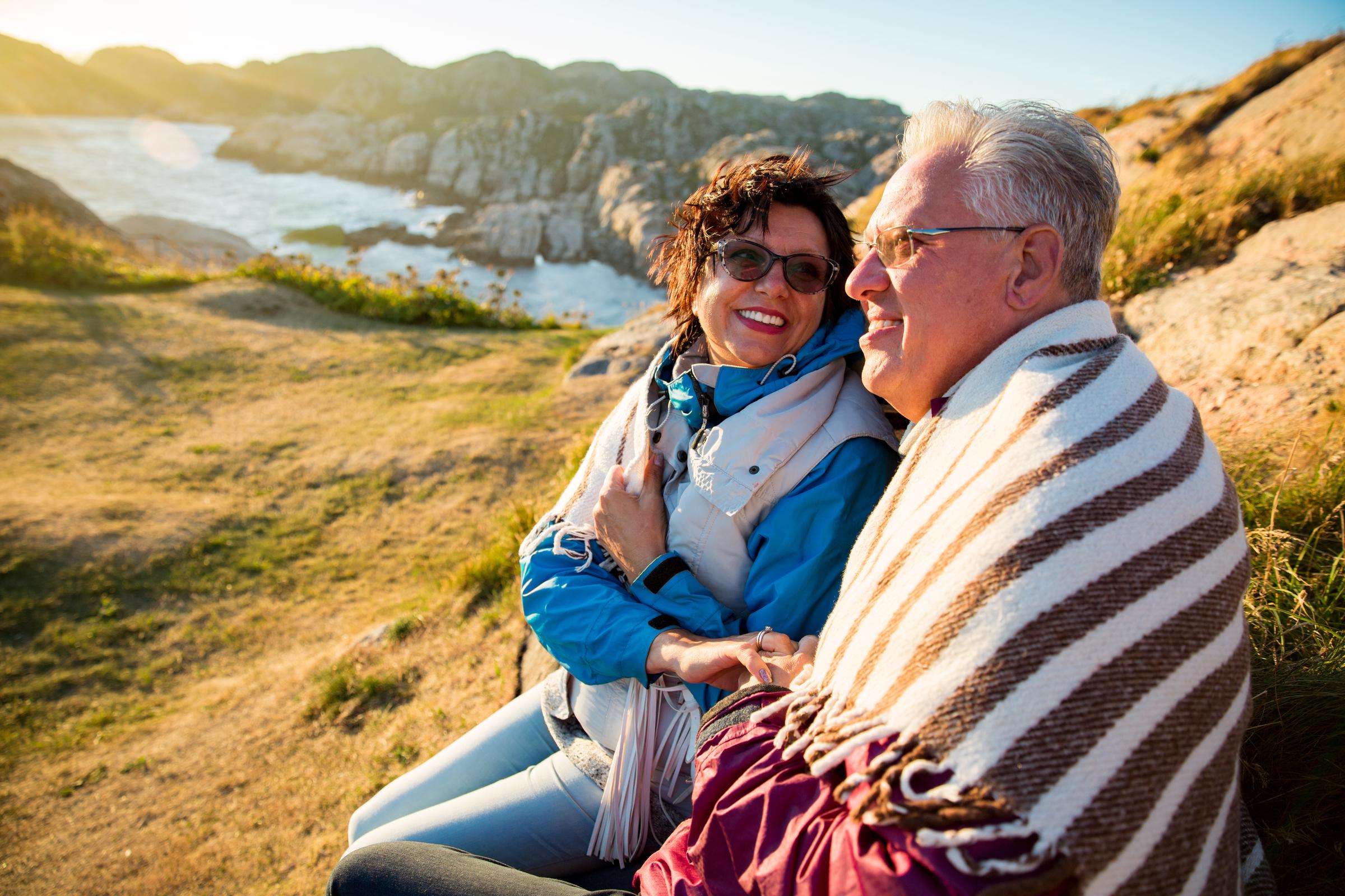 A couple of travelers smiling while sitting on a windy top of a rock formation | Source: Shutterstock