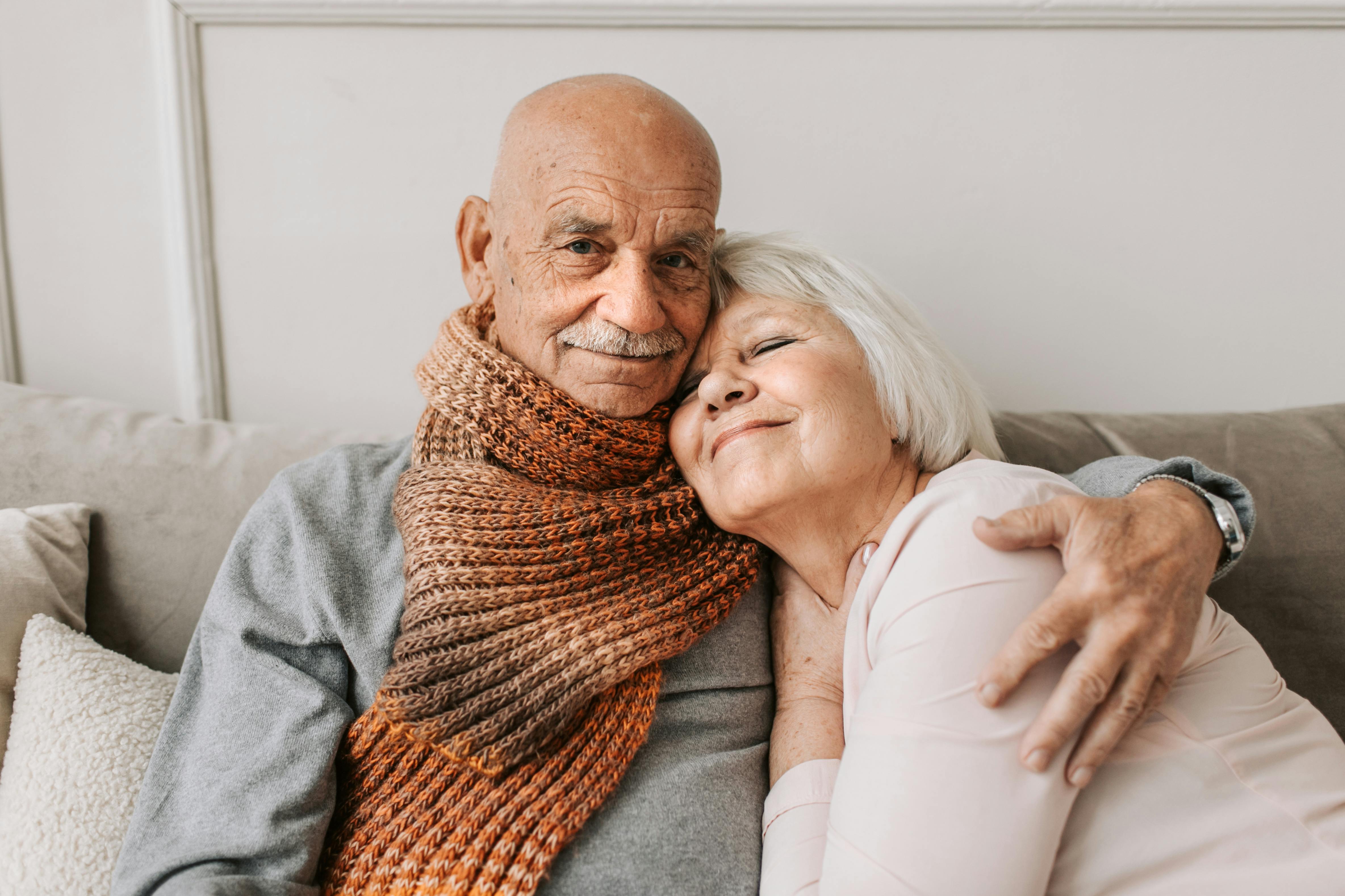 An older couple embraces while relaxing together on a couch at home. | Source: Pexels
