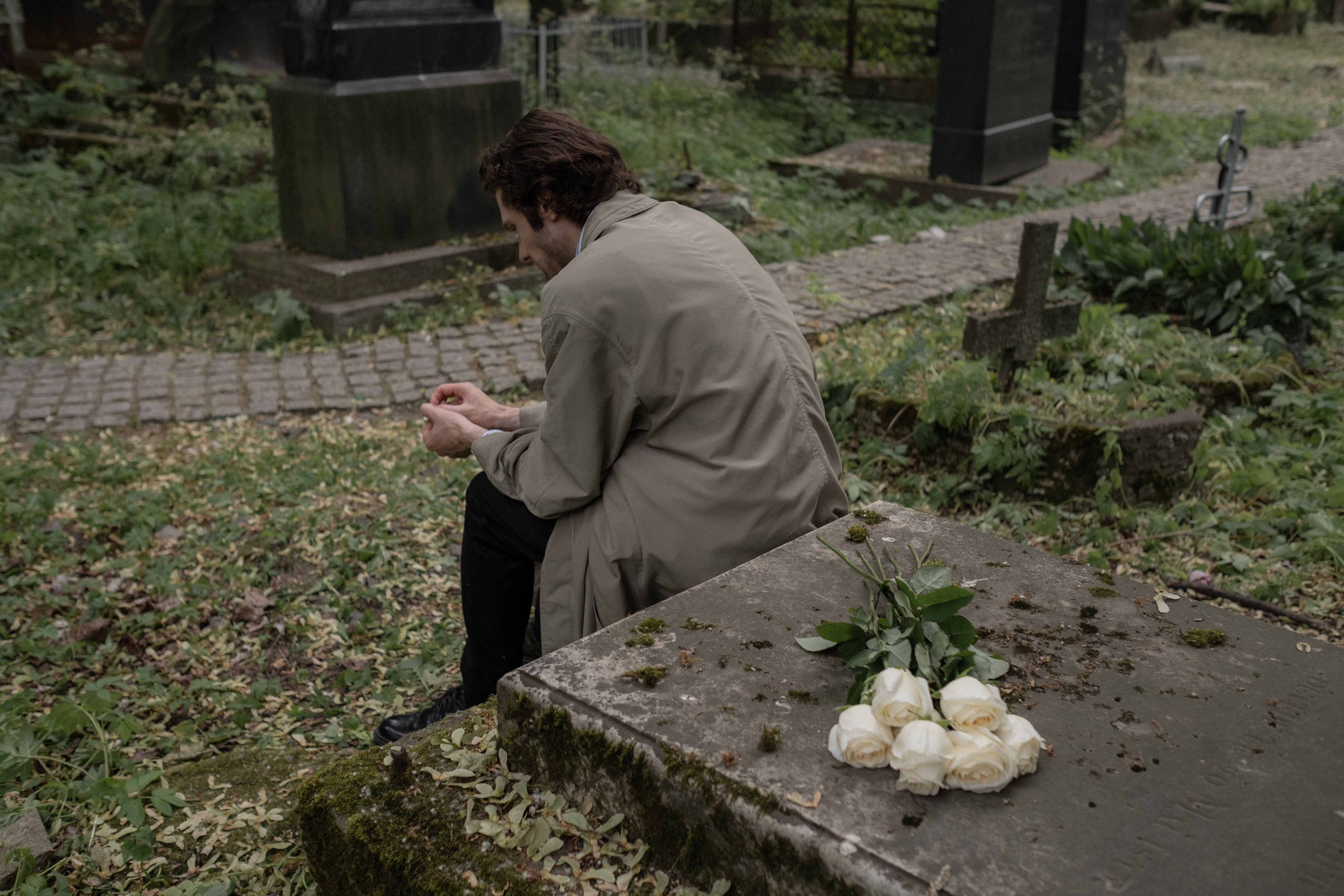 Hombre sentado sobre una tumba. | Foto: Pexels
