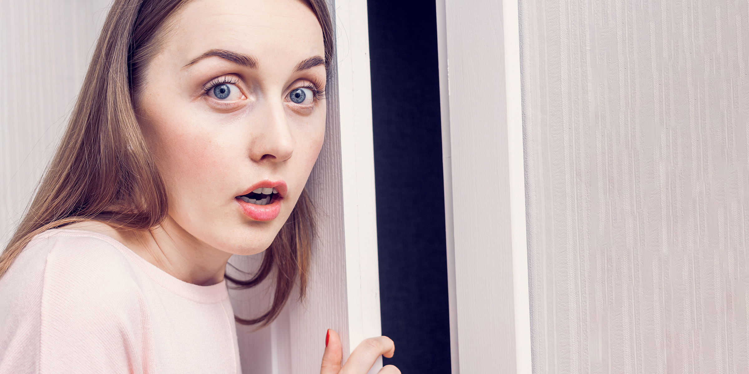 A shocked woman standing at a front door | Source: Shutterstock