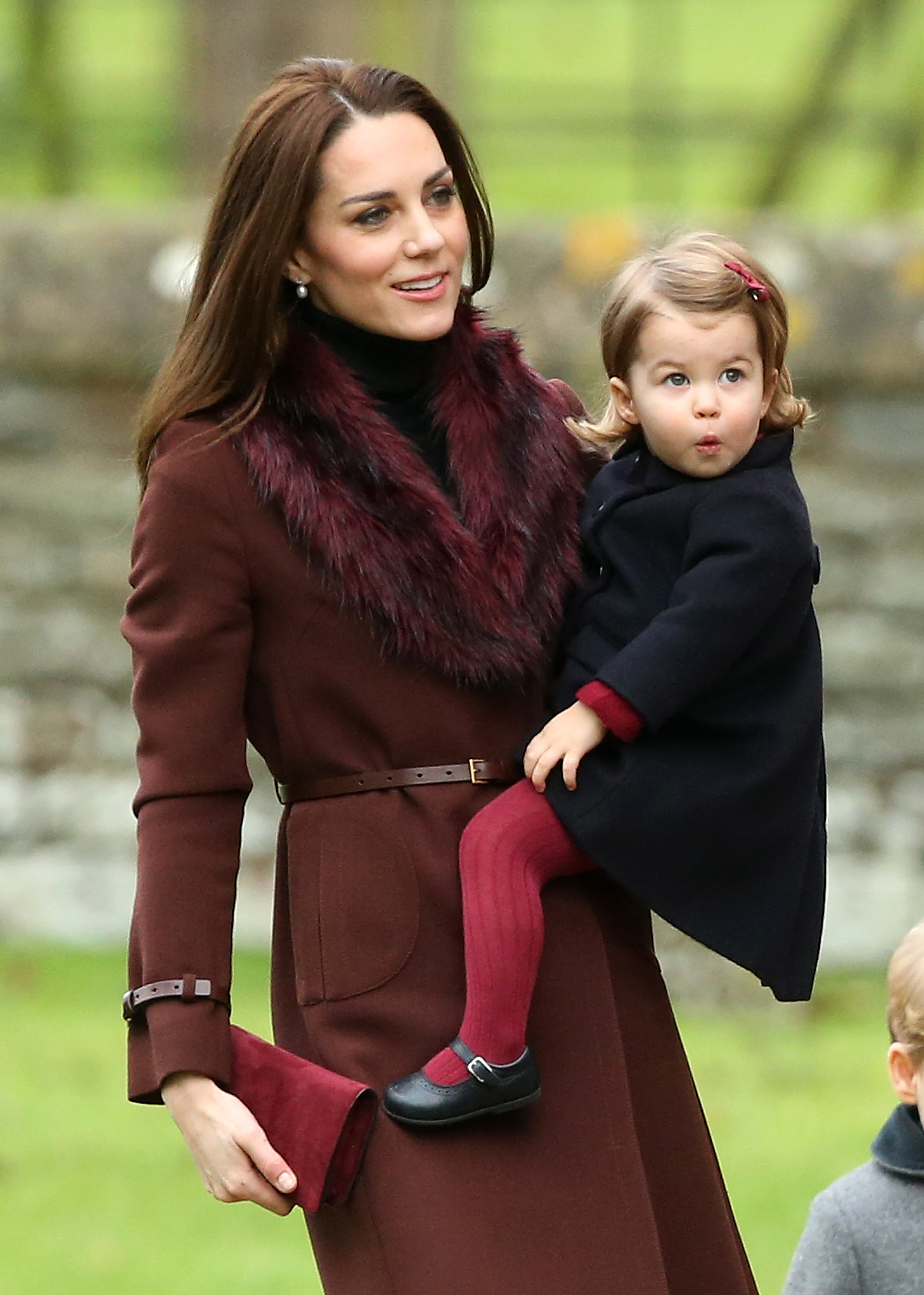 A wide-eyed, rosy-cheeked Charlotte — barely 18 months old, in a navy coat and crimson tights — gives the cameras a perfectly timed pout as Catherine carries her to the Christmas Day church service in Bucklebury, Berkshire, in 2016.