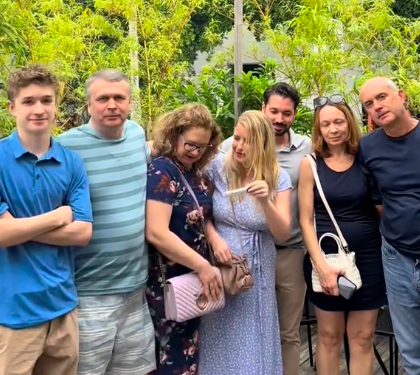 Olena Perez pulling out her pregnancy test and showing it to her mom, as her family pose for the camera. | Source: TikTok/@olena.perez