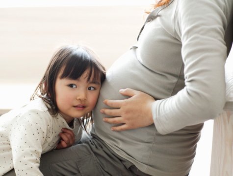 Little girl listening to pregnant mother's abdomen | Photo: getty Images