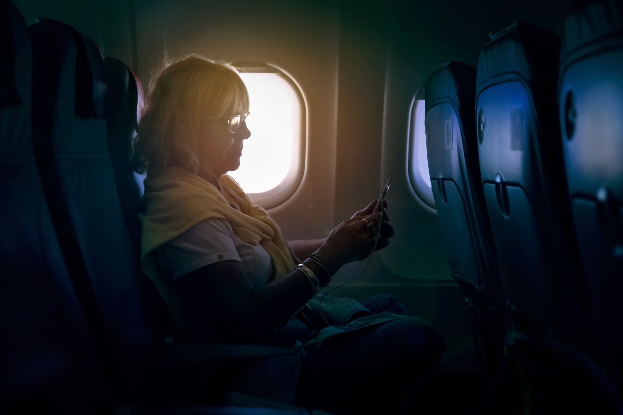 Senior woman using a smartphone on a plane | Photo: Getty Images