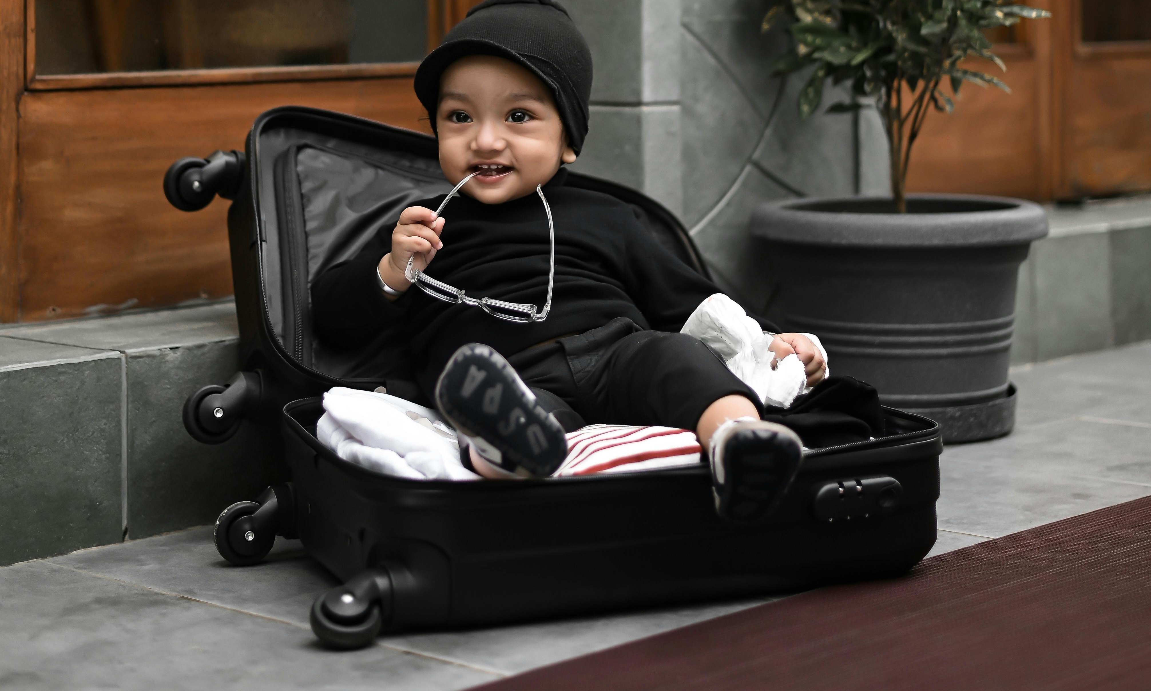 A baby sitting in an open suitcase | Source: Pexels