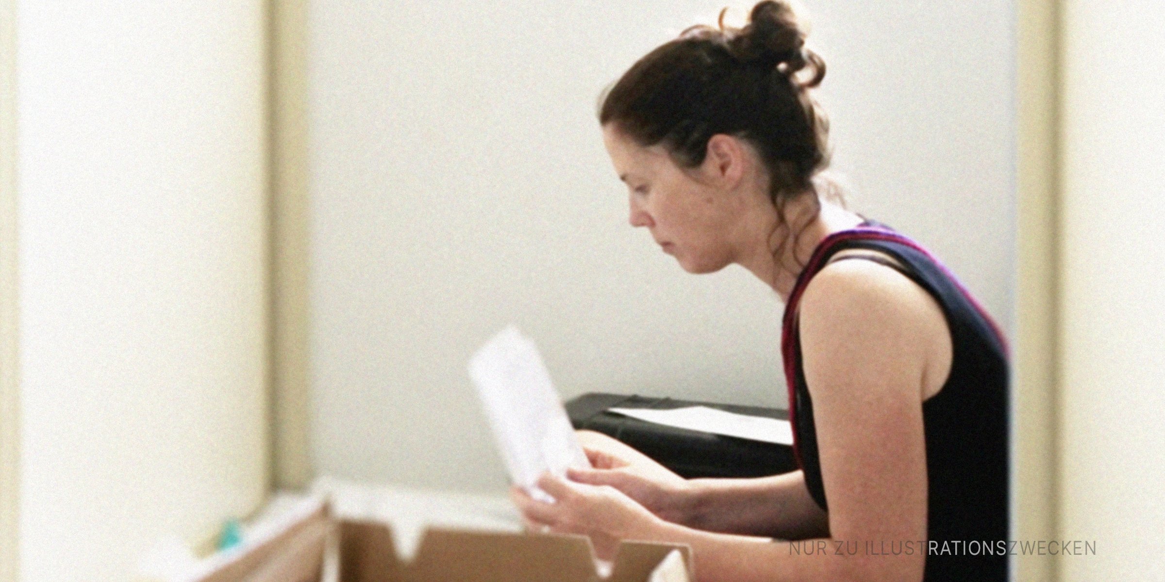 Frau liest einen Brief, der in einer Kiste gefunden wurde. | Quelle: Getty Images