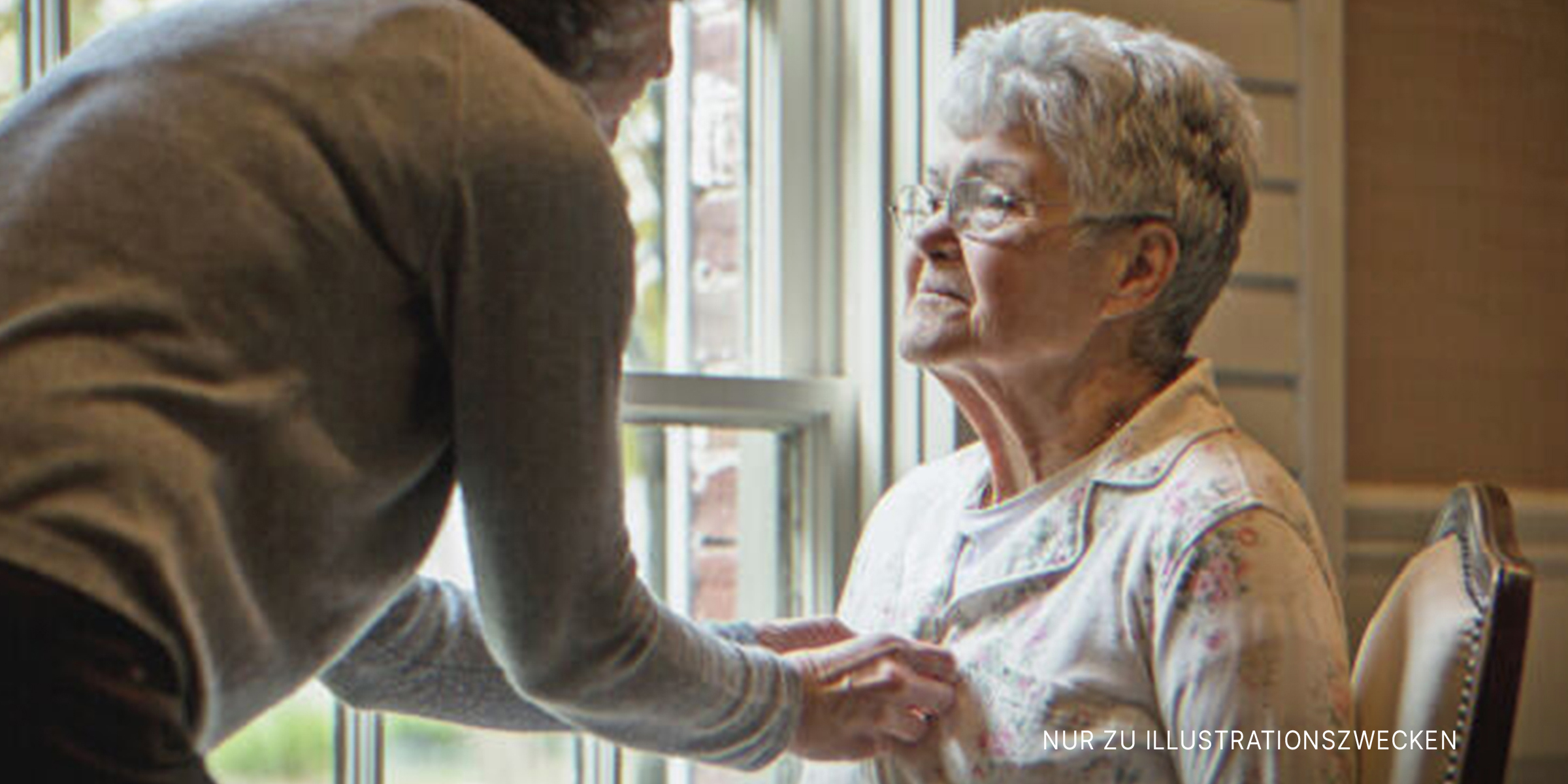 Alte Frau sitzt, während eine junge Frau ihr hilft. | Quelle: Getty Images