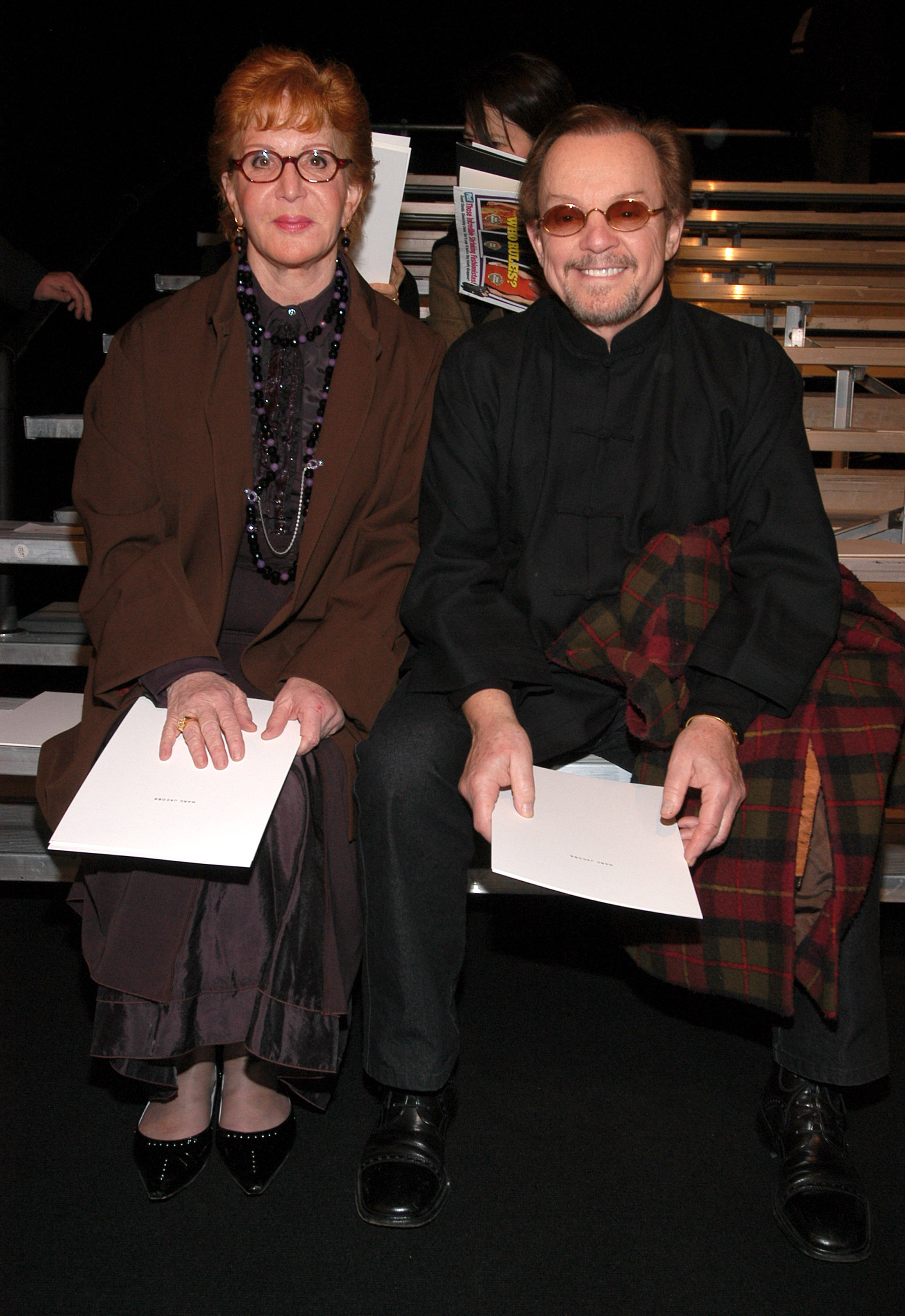 Sally Jessy Raphael and her husband, Karl Soderlund, sit front row at the Marc Jacobs Fall 2003 show during Mercedes-Benz Fashion Week at the New York State Armory. Dressed in layered neutrals and holding show programs, the couple watches the runway amid the high-fashion buzz.