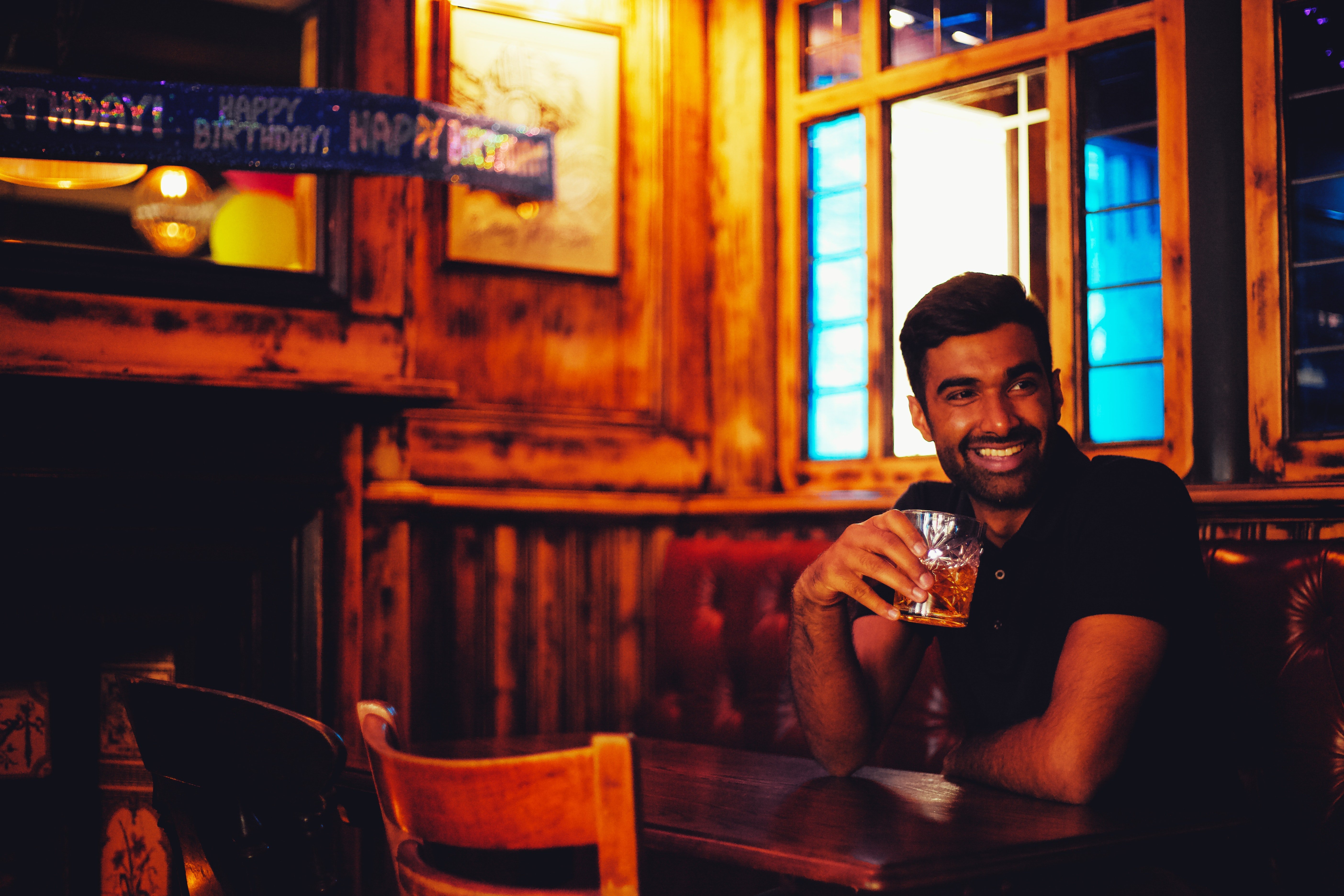 Man smiles while drinking alcohol. | Source: Pexels