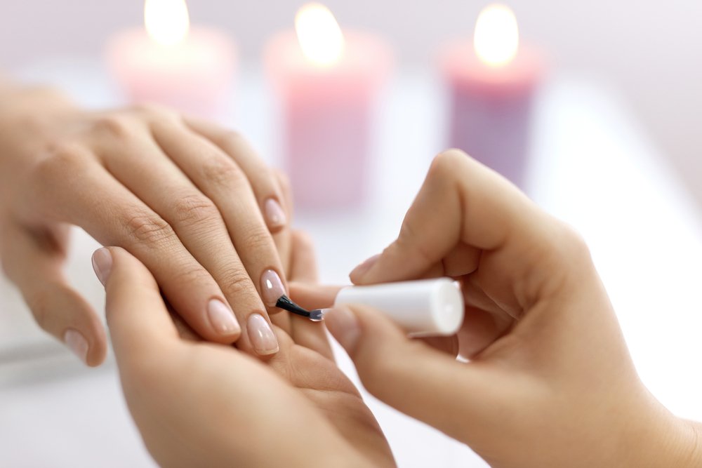 Mujer aplicando esmalte a las uñas de otra mujer. | Foto: Shutterstock