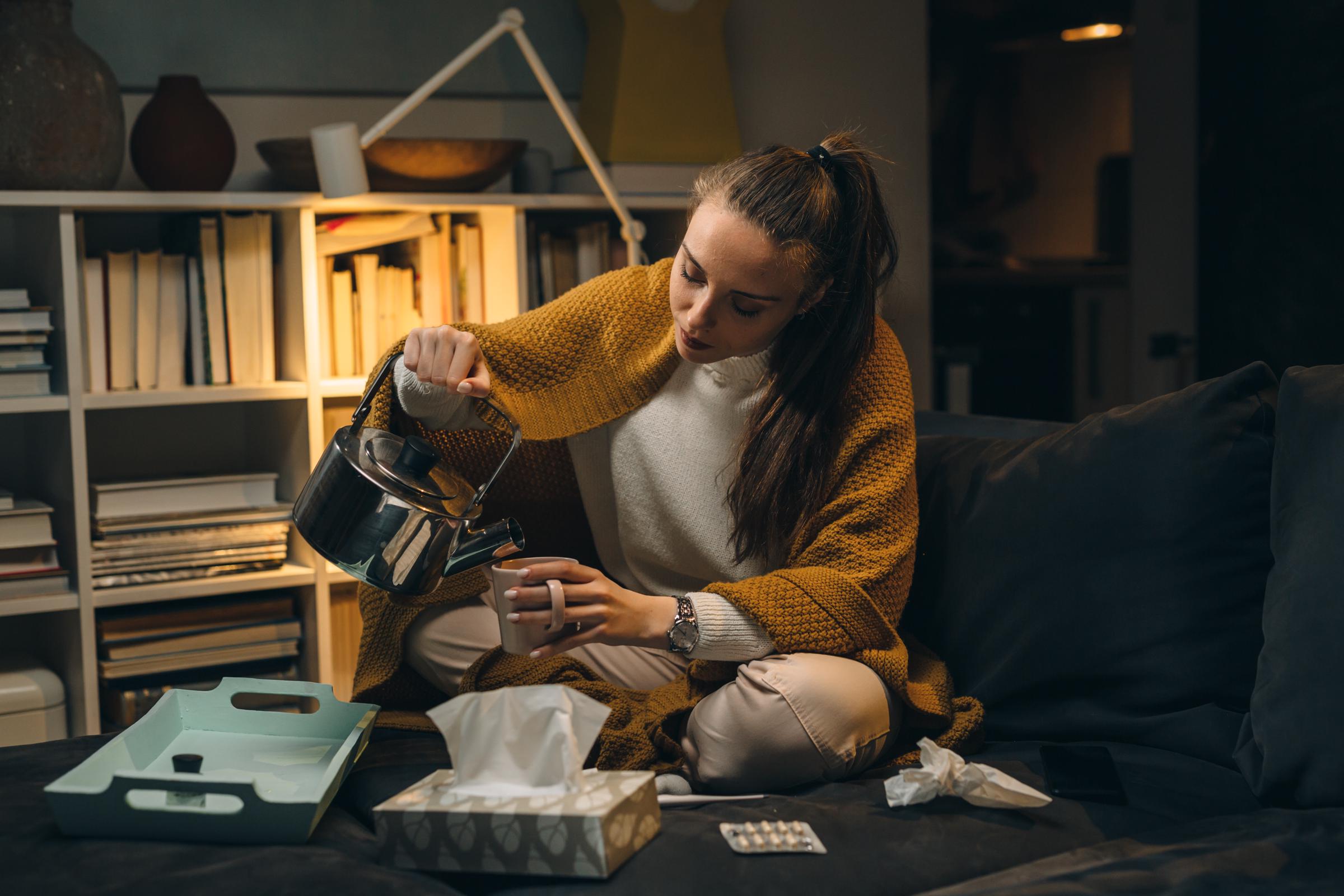 A woman pouring tea into a cup at night | Source: Shutterstock