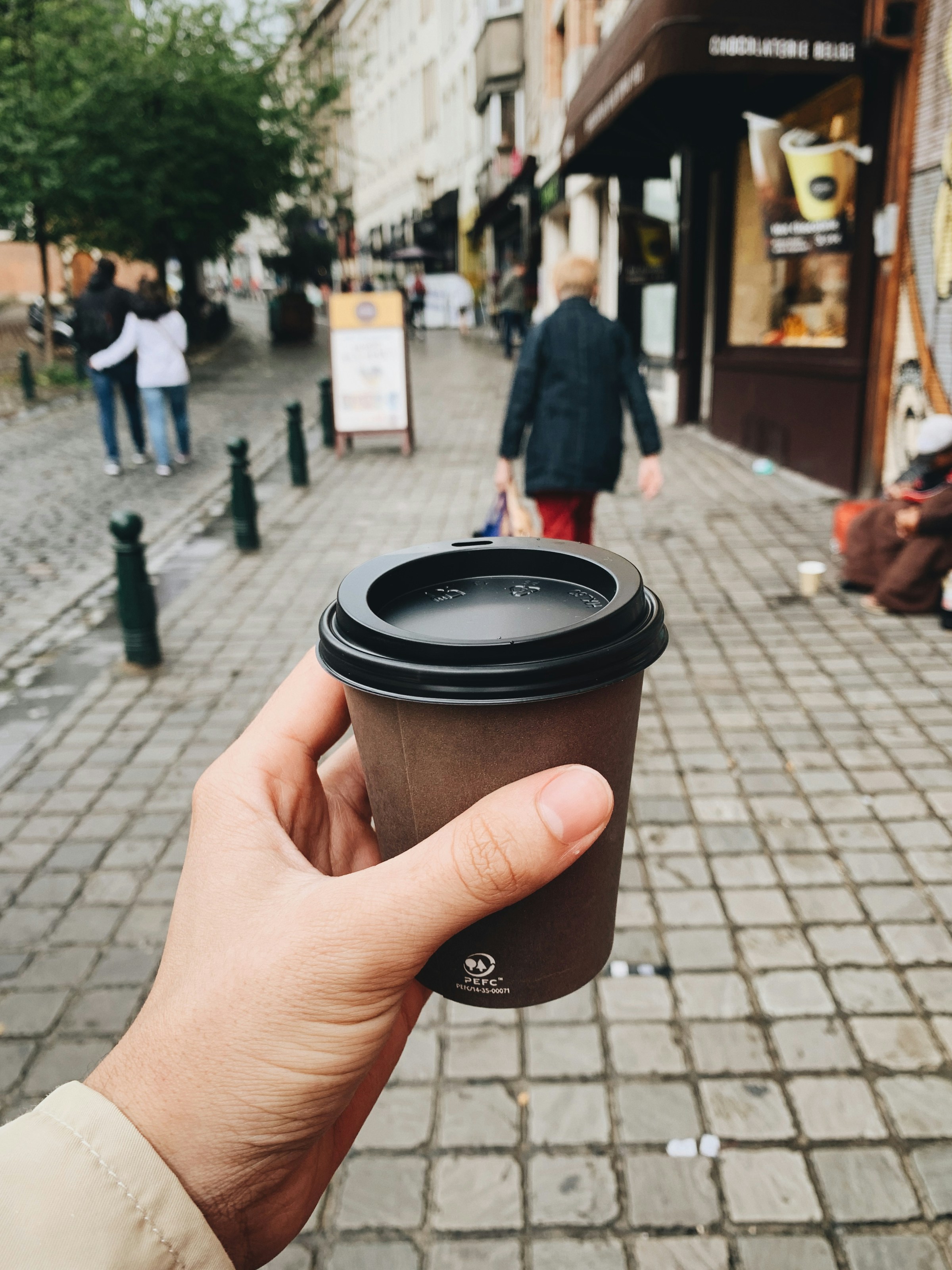 A person holding a takeaway coffee cup | Source: Unsplash