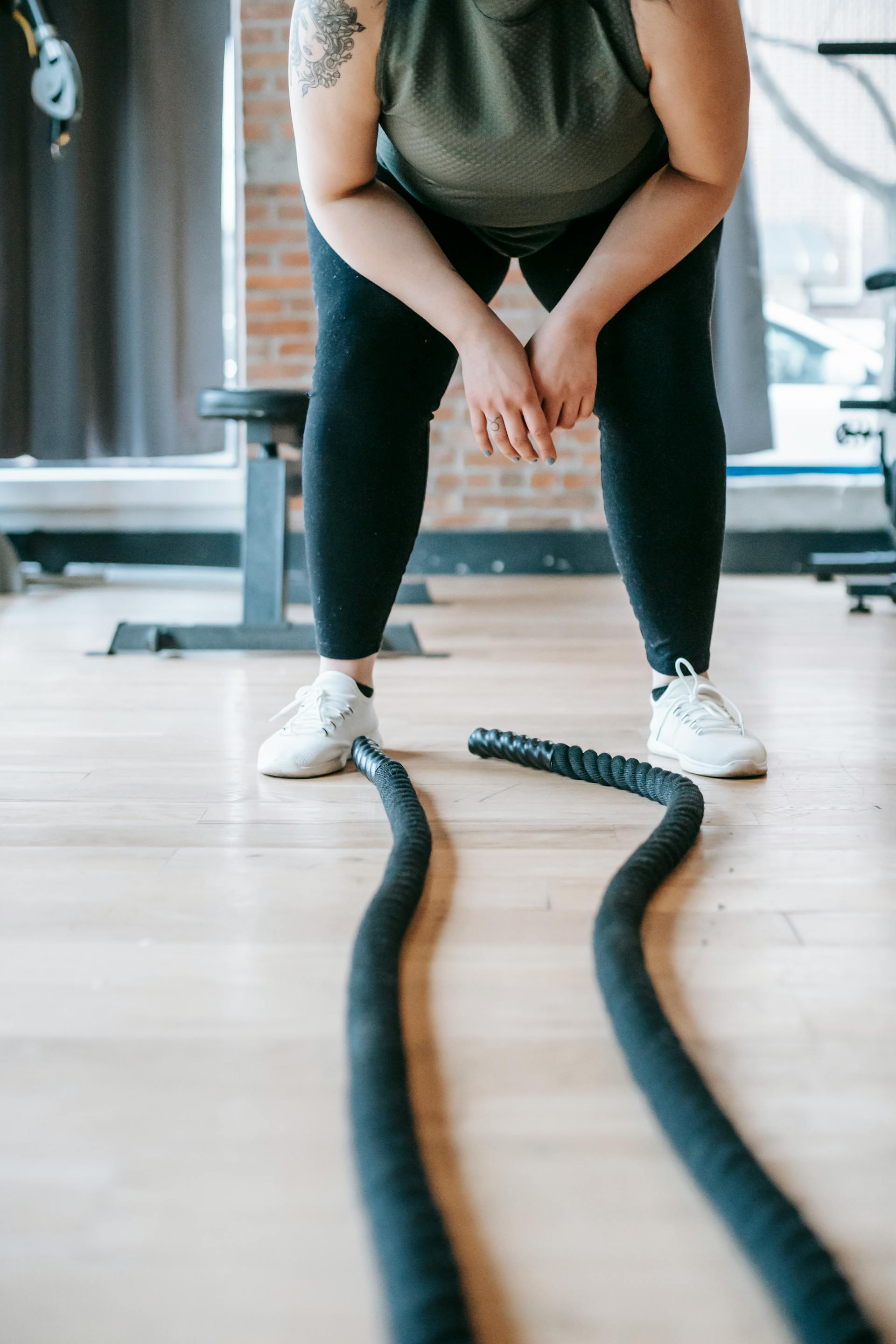 A plus-size woman resting after exercising with battle ropes | Source: Pexels