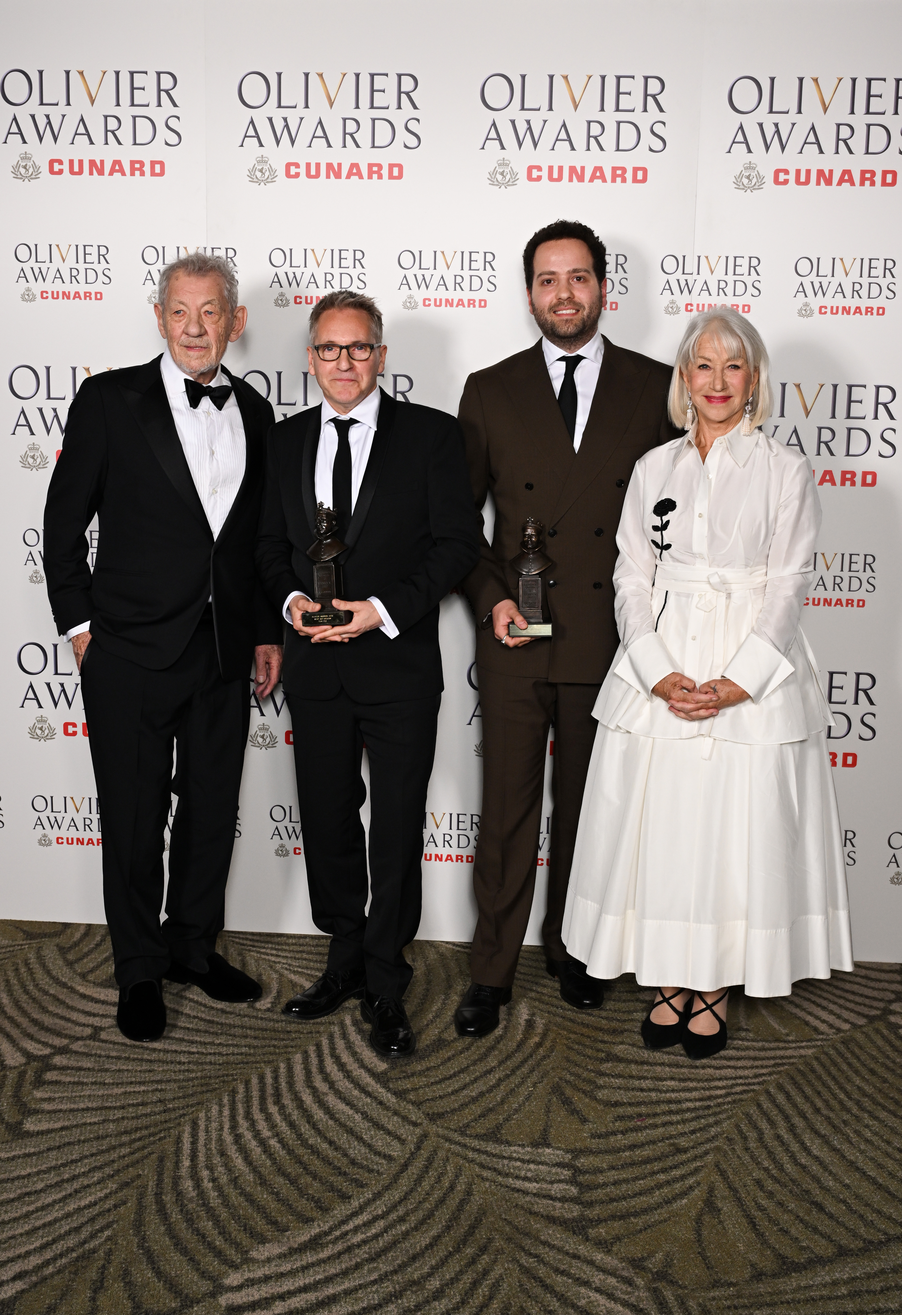 Sir Ian McKellen, Tom Pye, Ash J. Woodward, and Dame Helen Mirren pose inside the Winners Room during The Olivier Awards 2026 on 12 April in London, England. | Source: Getty Images