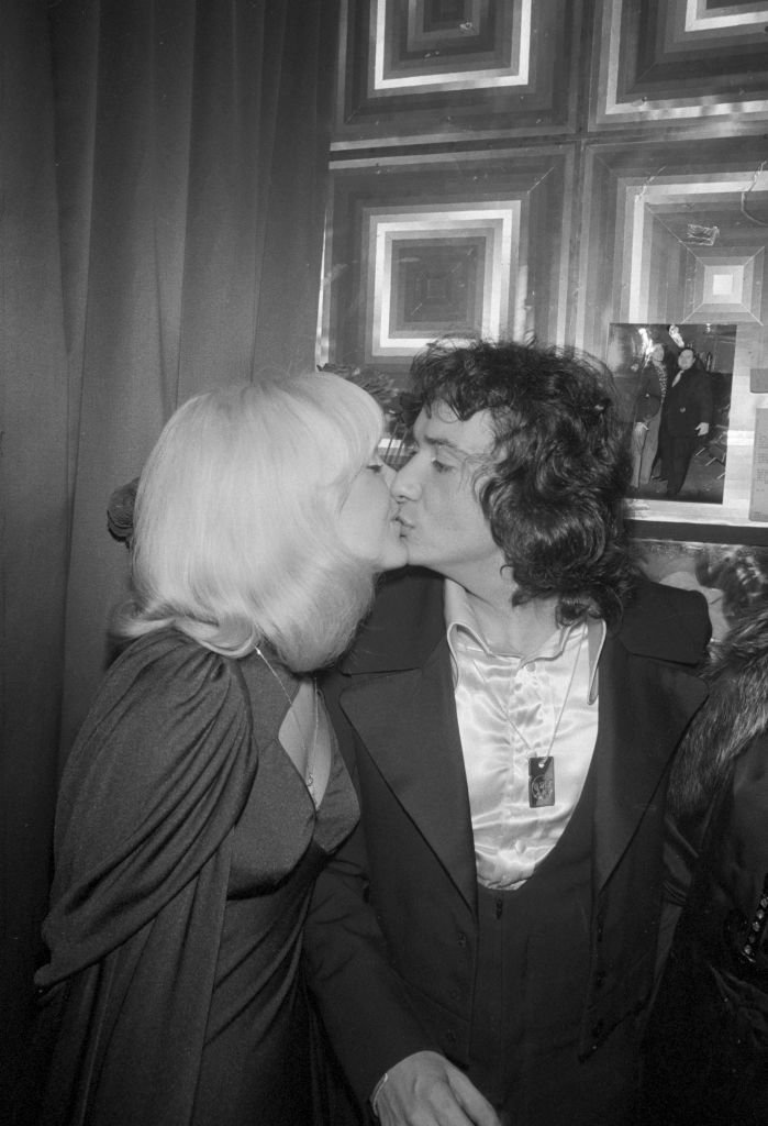 Michel Sardou embrasse sa compagne Babette dans sa loge après son concert à l'Olympia de Paris le 30 décembre 1974, France | Source : Getty Images
