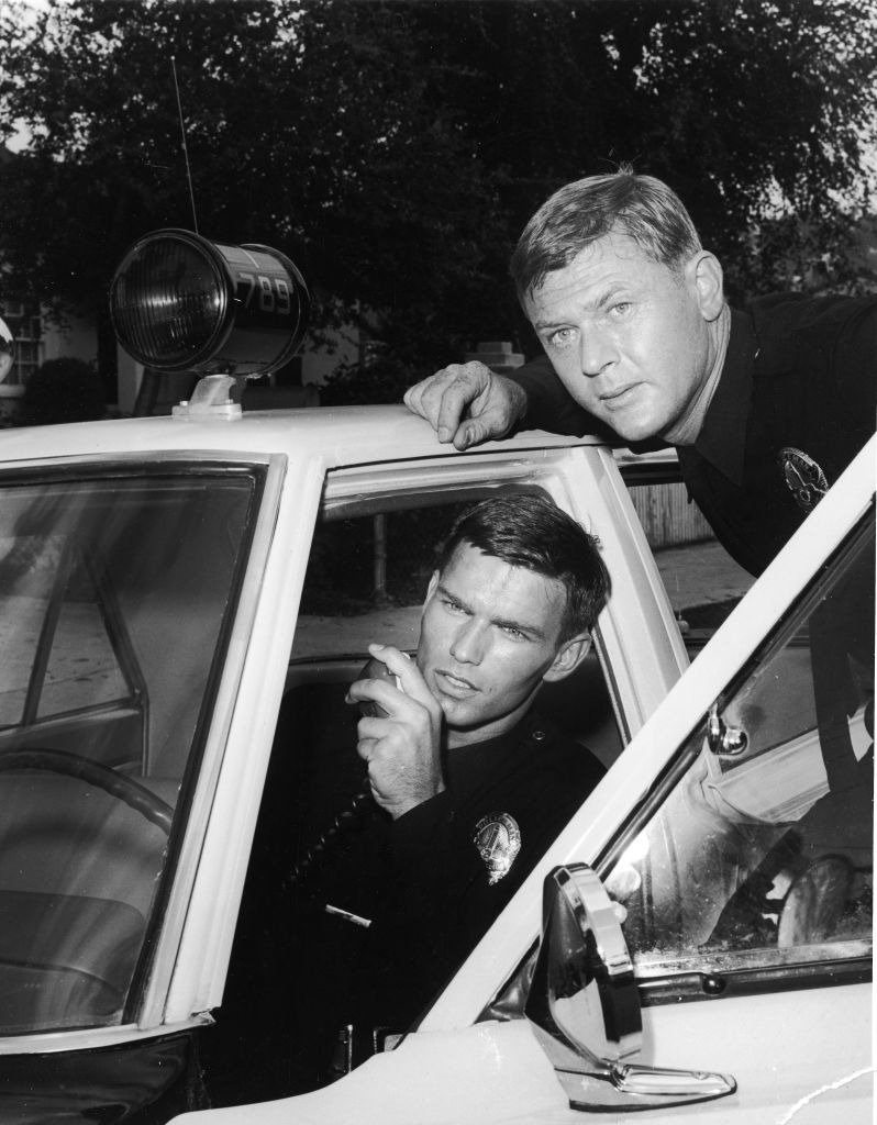 Actor Martin Milner leans over the door of a patrol car as Actor Kent McCord talks on the police radio in a promotional still for the TV series, 'Adam 12,'. | Source: Getty Images