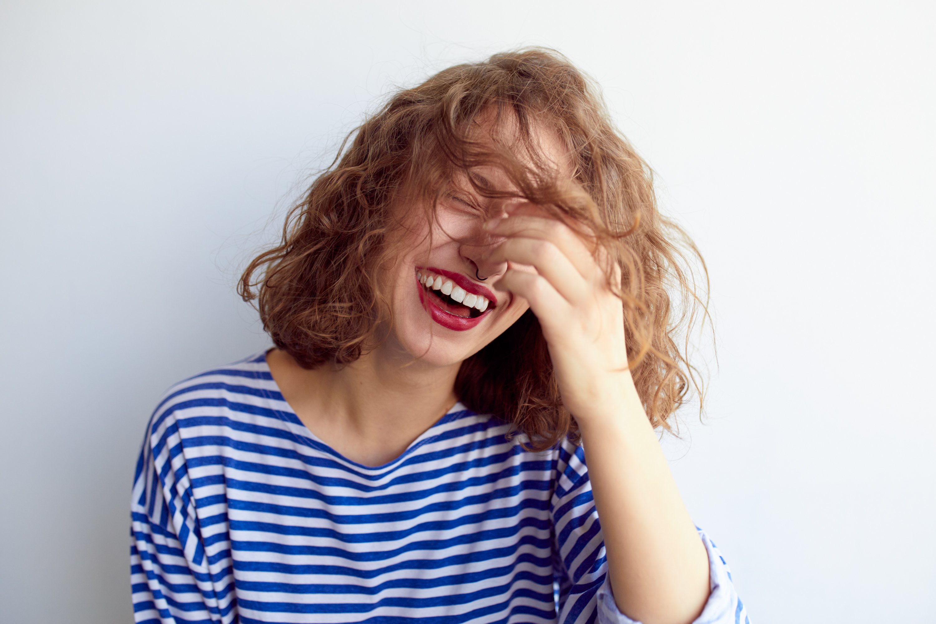 Woman in striped T-shirt laughing.|Source: Shutterstock