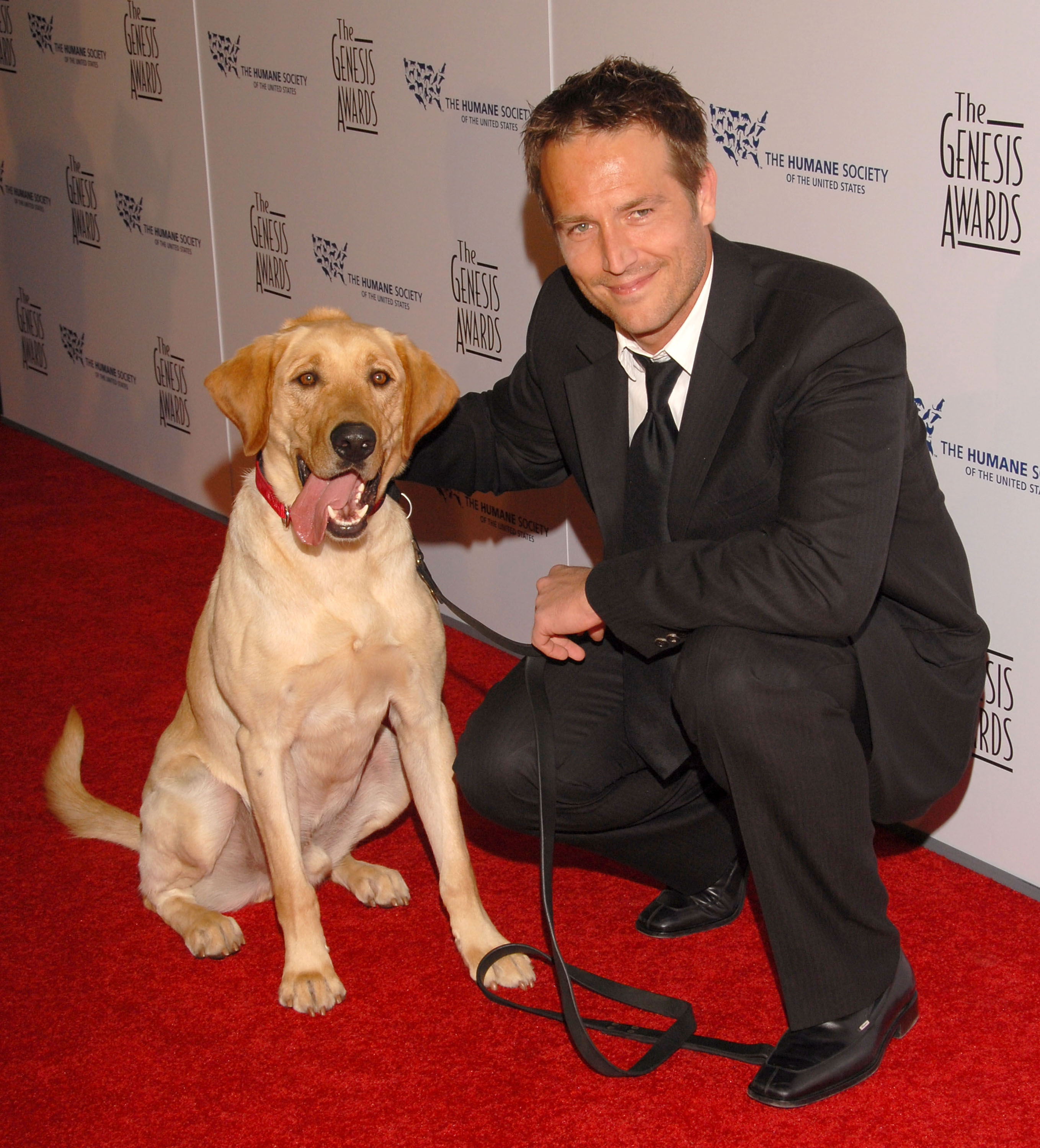 Michael Vartan crouches beside a dog on the red carpet at the Genesis Awards. His warm smile and gentle presence reflect his love for animals and low-key public appearances.