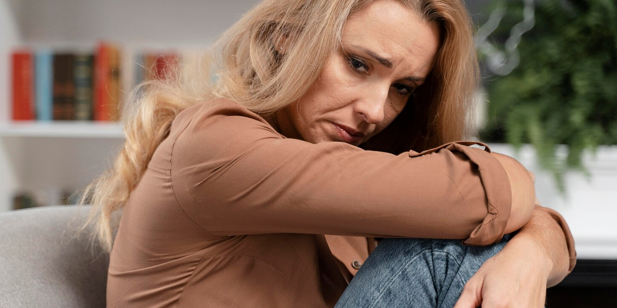 A distressed woman hugging her knees | Source: Freepik