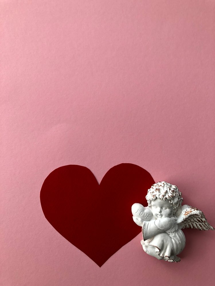 Angel baby artwork on a pink background with a red heart | Photo: Shutterstock/Assa2215