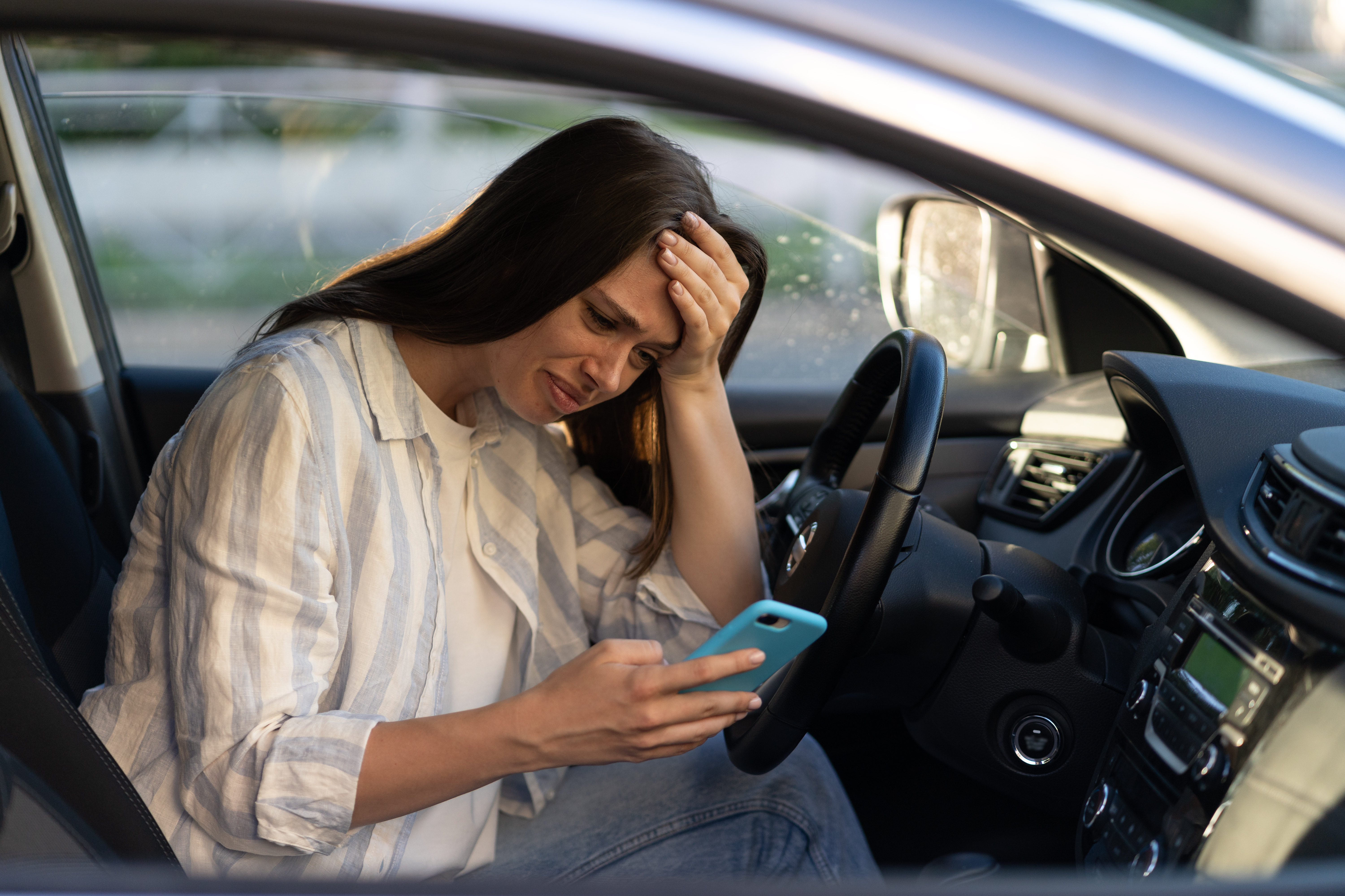 Unhappy girl cry reading sms message in smartphone driving car. Upset female break up with boyfriend | Source: Getty Images