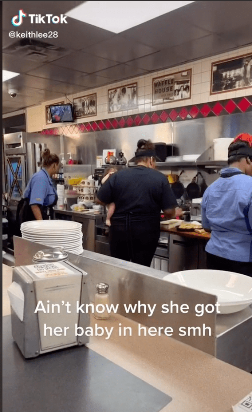 A Waffle House worker carries a child while preparing food for customers. | Source: Tiktok.com/kizzle360
