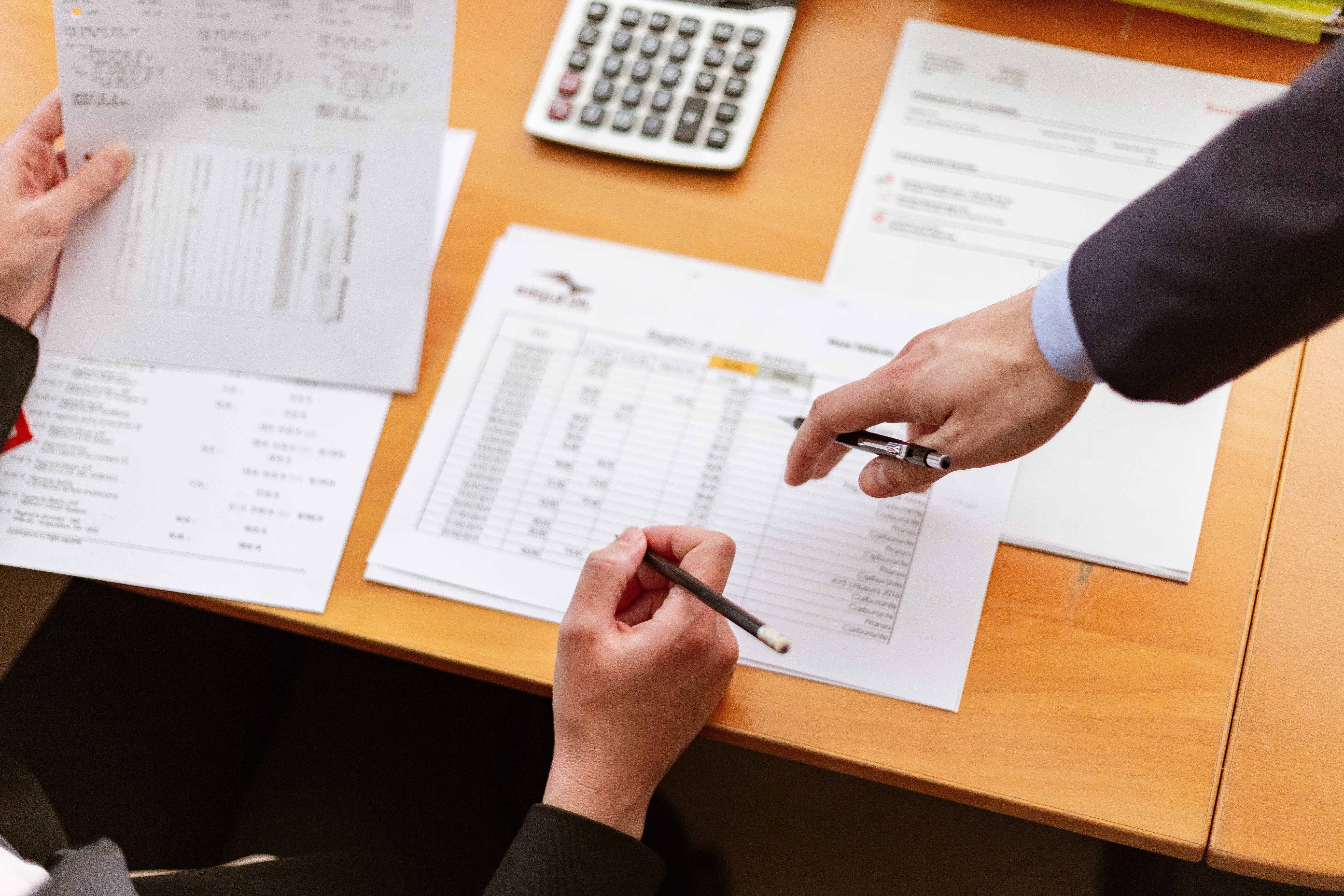 Paperwork lying on a desk with hands above it. | Source: Pexels/ Oleg Magni