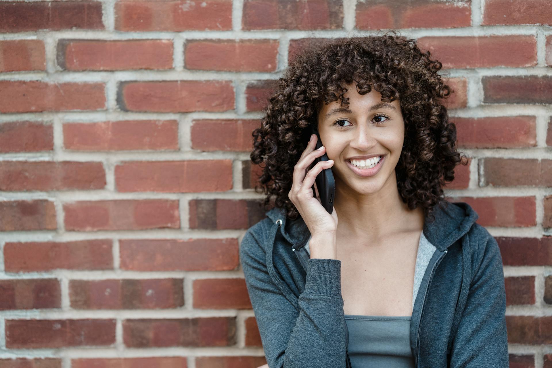 A woman smiling while on a phone call | Source: Pexels