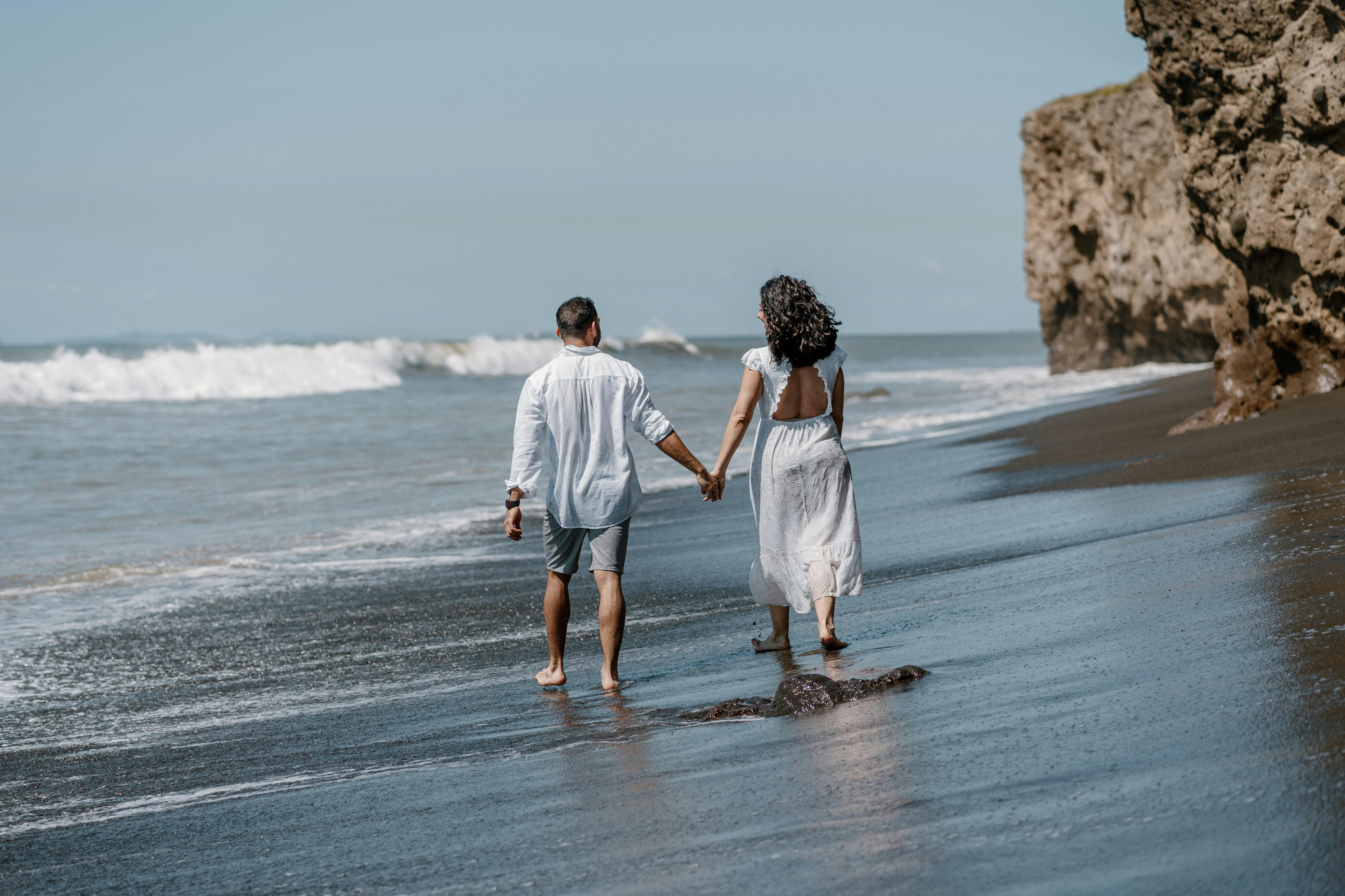 A couple holding hands on the beach | Source: Pexels