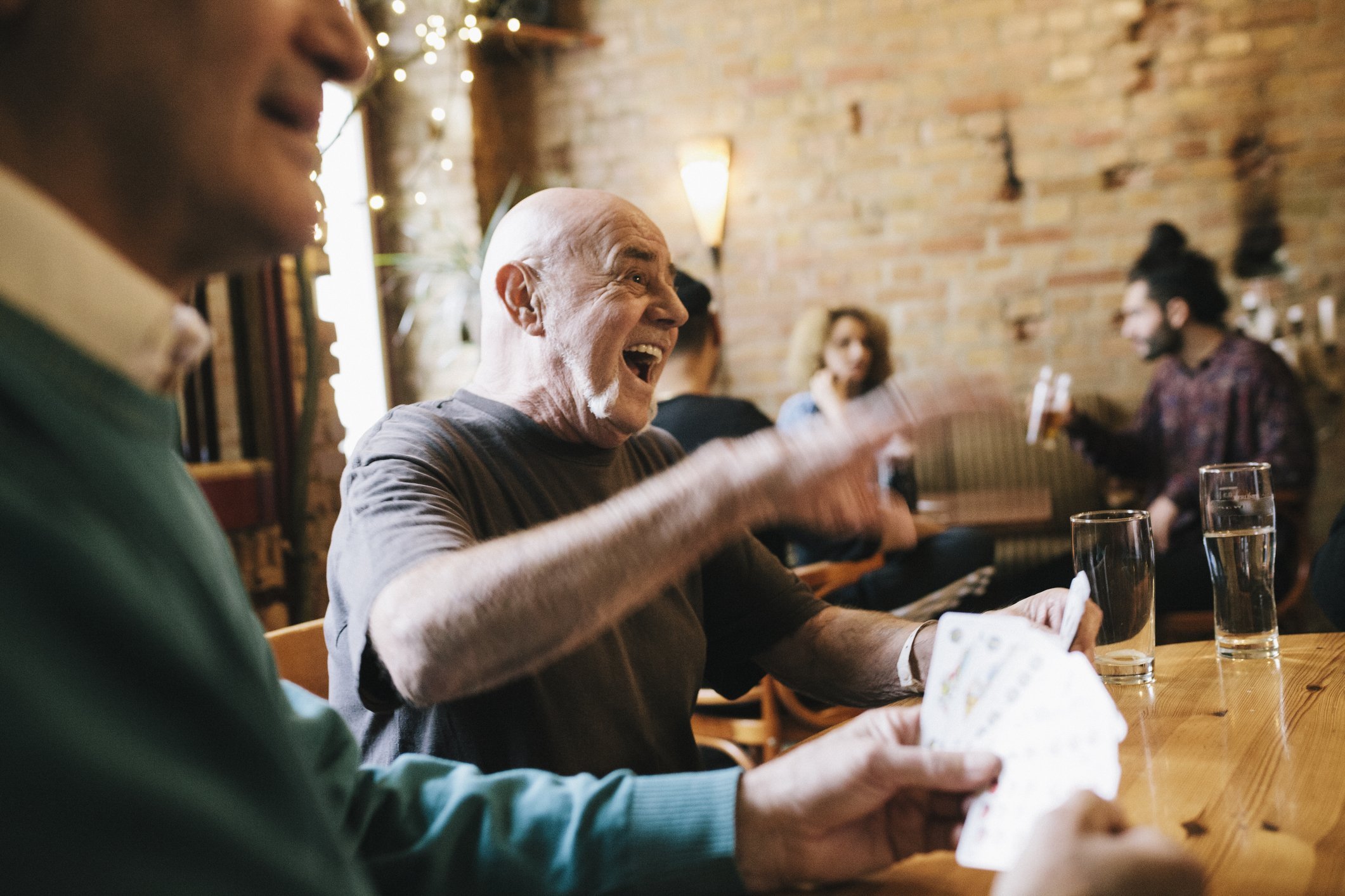 An image of an old man laughing during a card game. | Photo: Getty Images