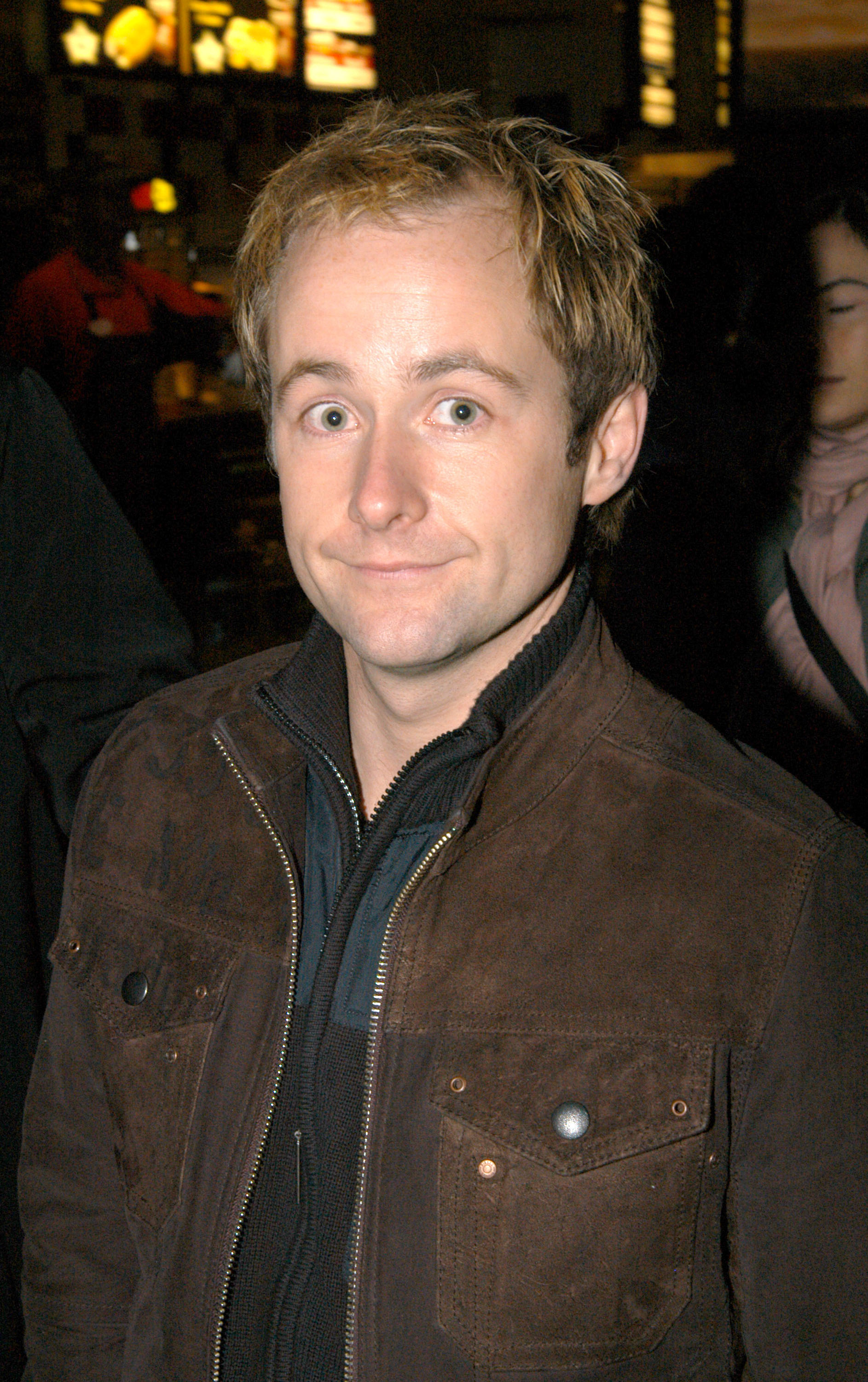 Billy Boyd attends a special screening of The Lord of the Rings: The Return of the King in New York City in 2003, wearing a brown suede-style jacket over a dark zip-up top, his wide-eyed look paired with a subtle, relaxed smile.