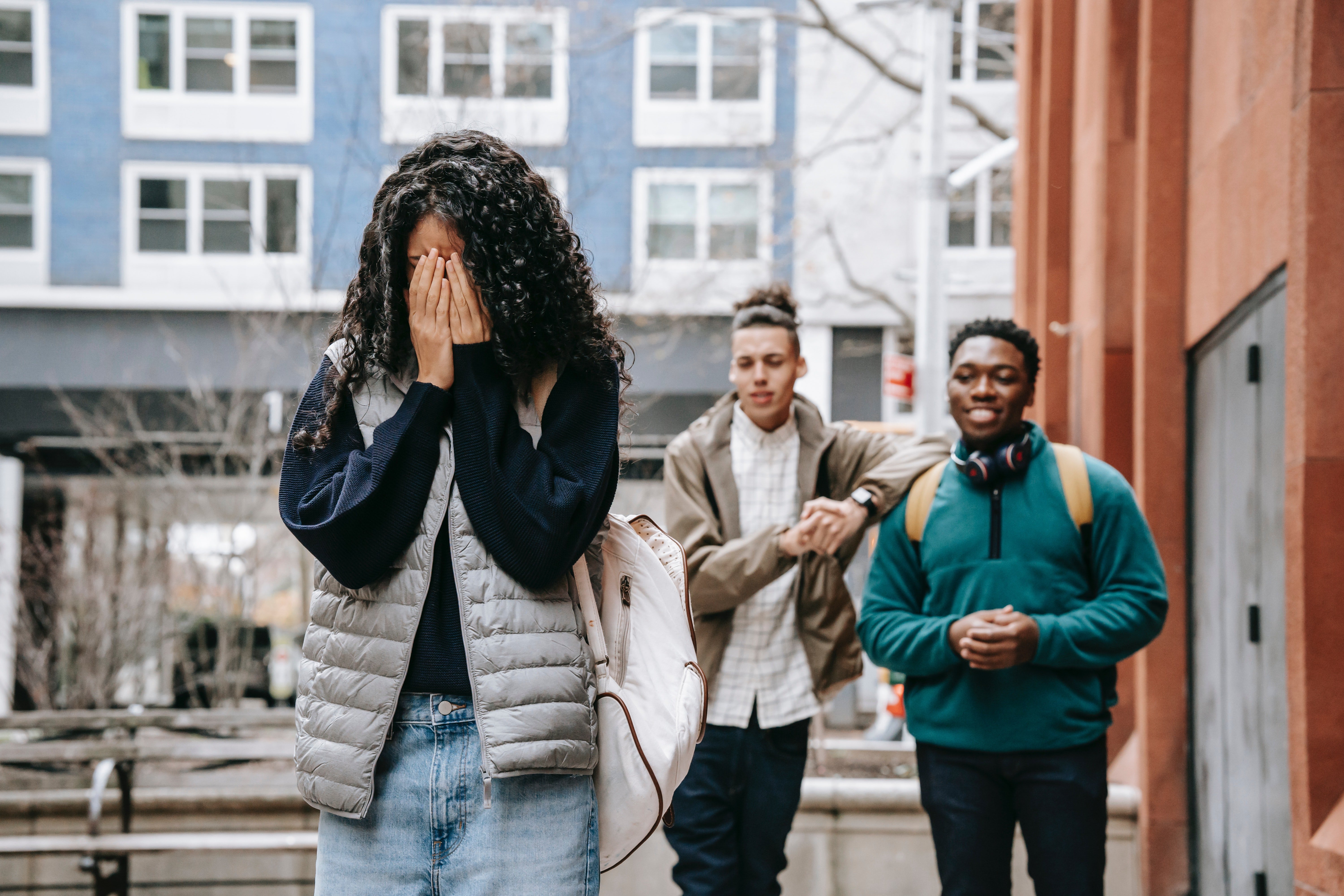 Pictured - Two male teens bullying a young woman who covers her face | Source: Pexels