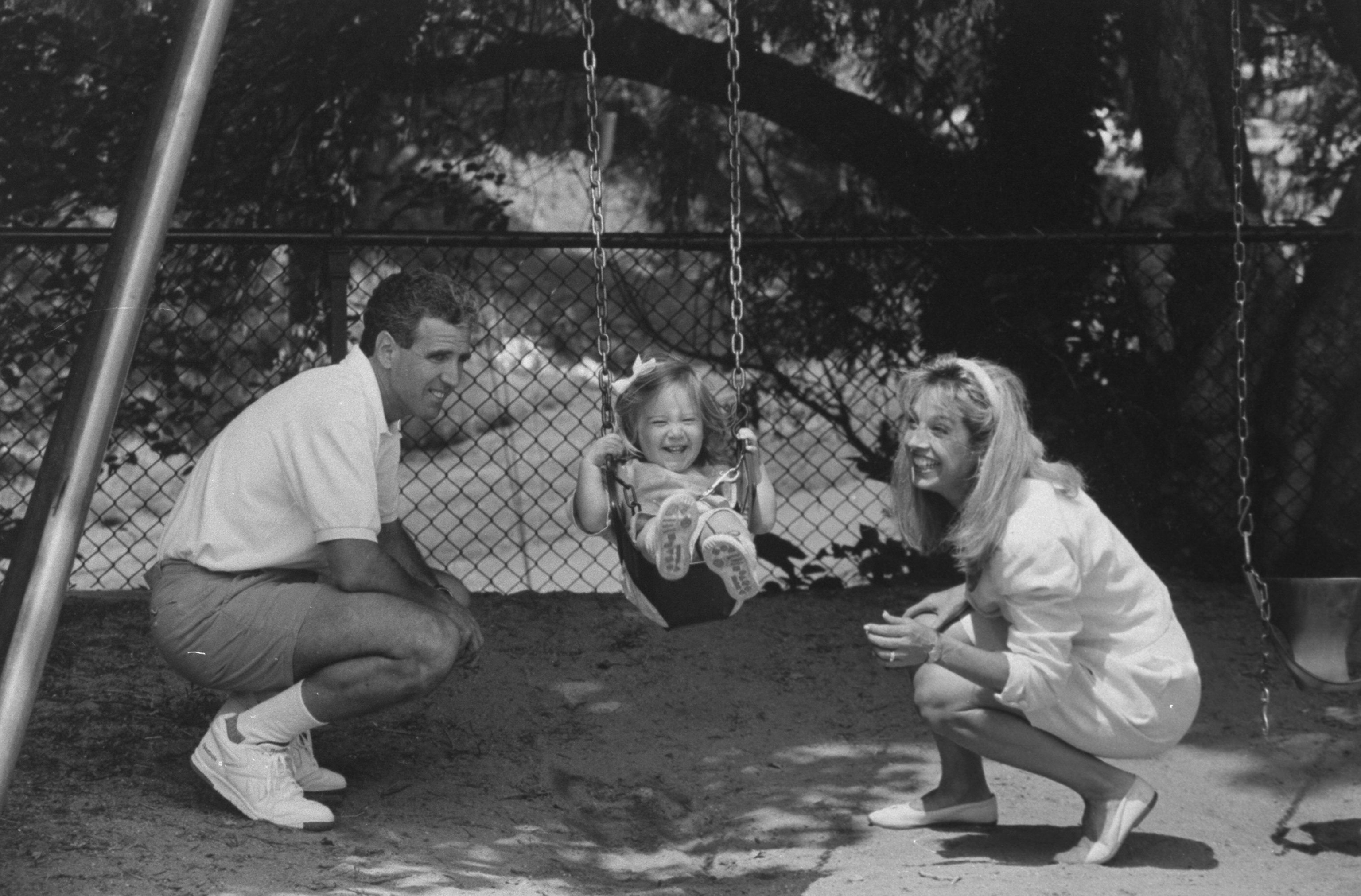 Denise Austin, Jeff Austin and their 21-month-old daughter, Kelly, on a swing at a park near their home, on June 3, 1992 | Source: Getty Images