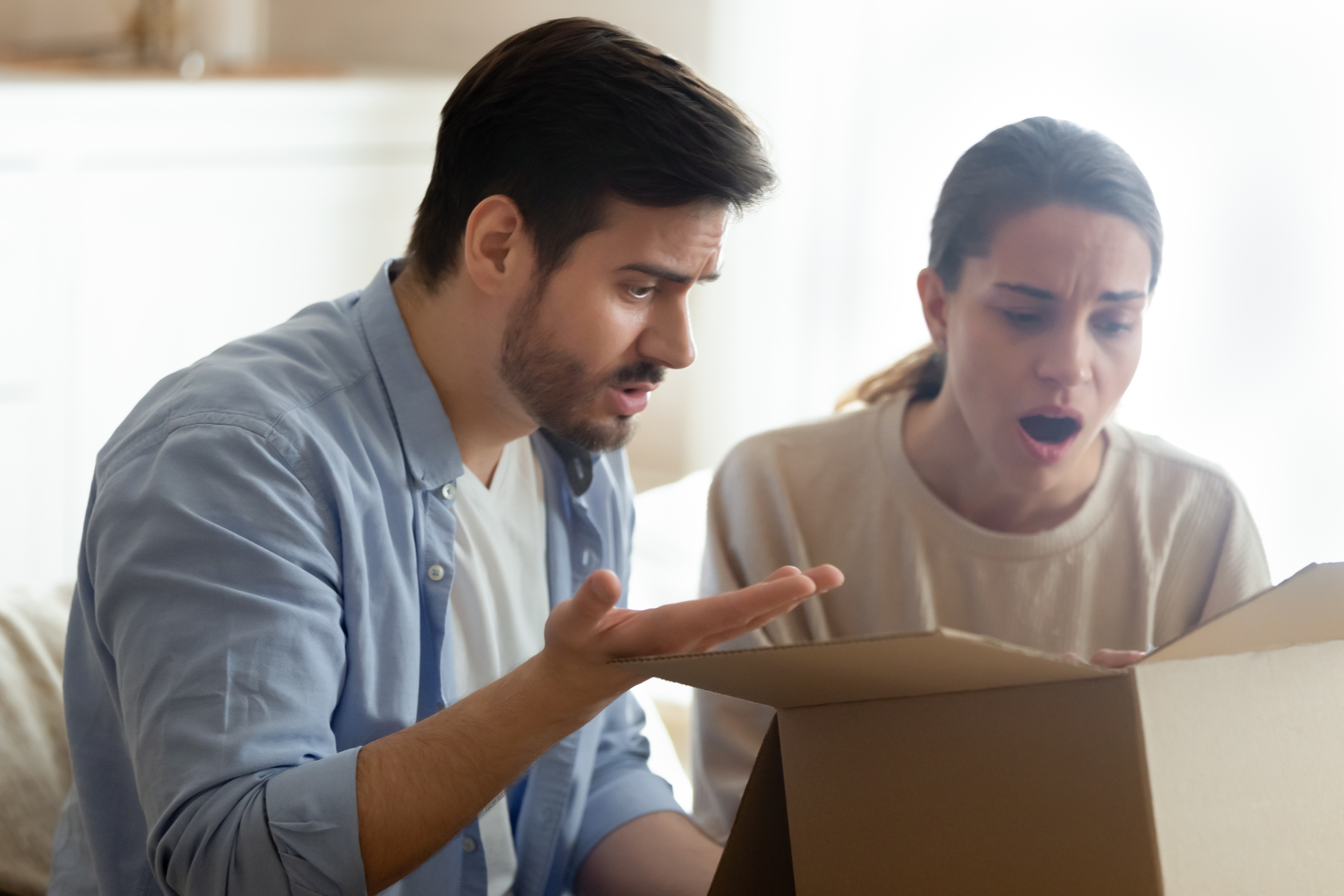 An annoyed couple staring at a delivery box | Source: Shutterstock