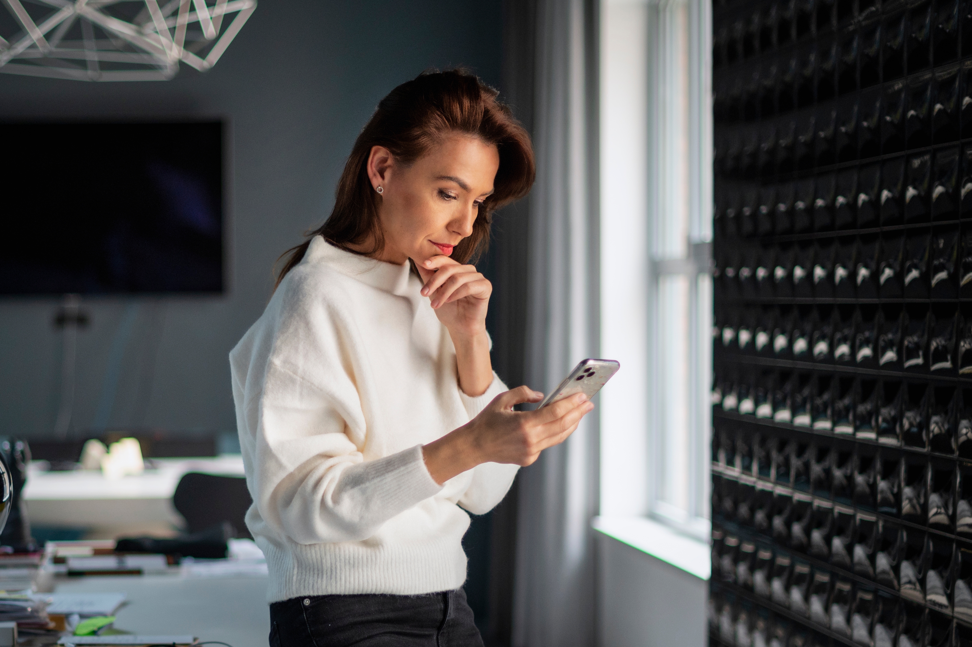 A middle-aged businesswoman standing in the office and using a smartphone. | Source: Shutterstock