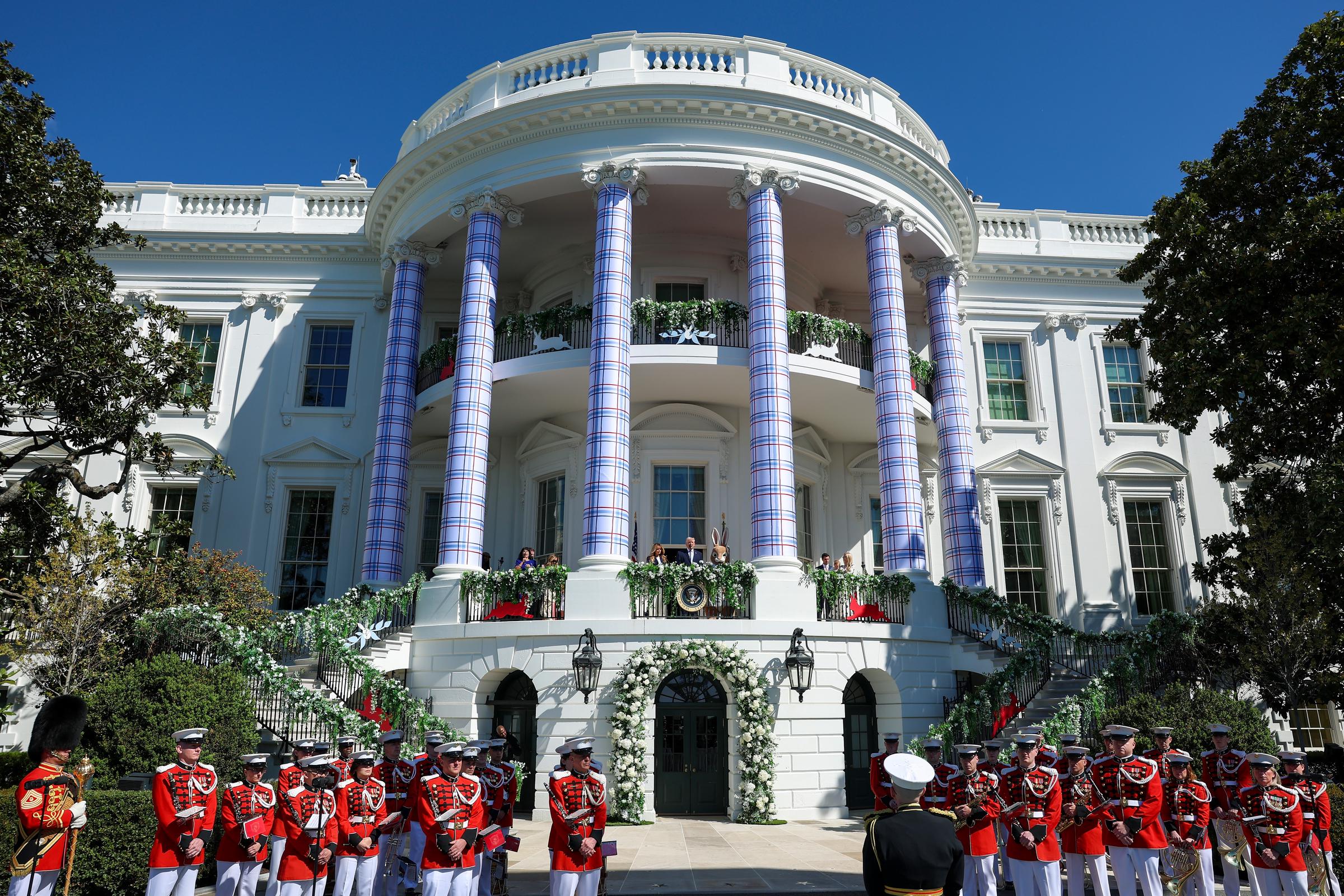 U.S. President Donald Trump and First Lady Melania Trump stand on the White House balcony beside the Easter Bunny, framed by spring florals, during the 2026 Easter Egg Roll, a tradition dating to 1878 that also marked the nation's 250th anniversary.