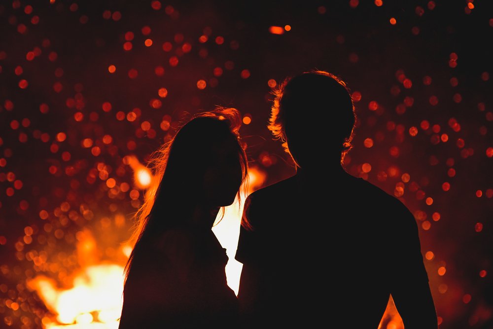 Joven y mujer enamorados de pie junto al gran incendio. | Foto: Shutterstock