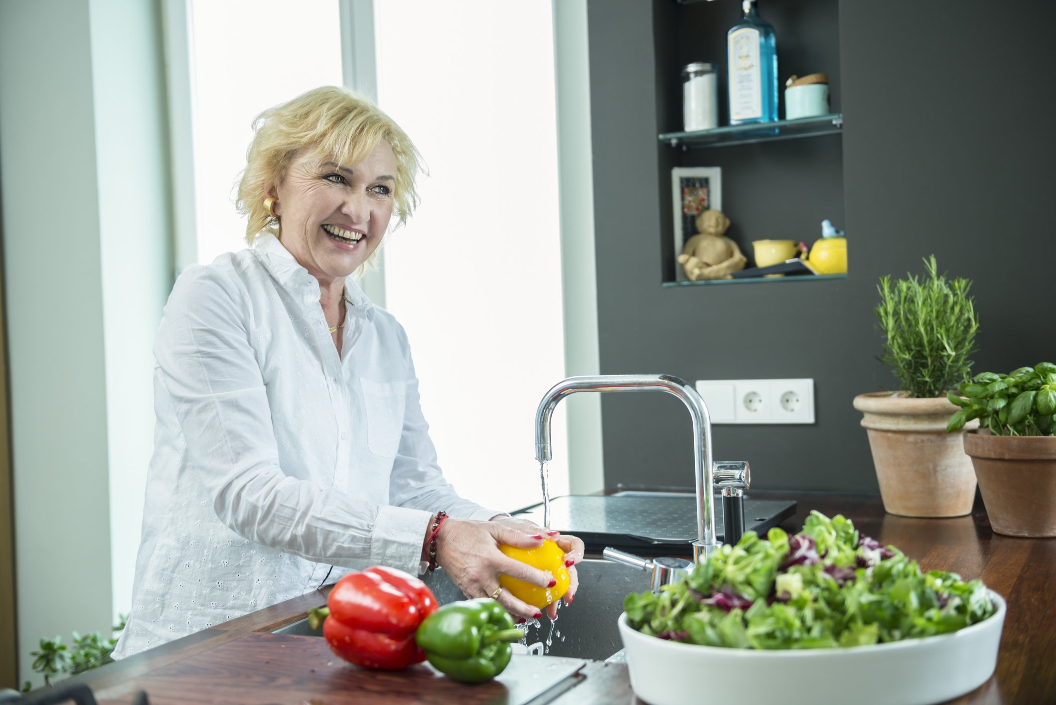 Une femme lavant des légumes à l'évier de la cuisine. | Photo : Getty Images