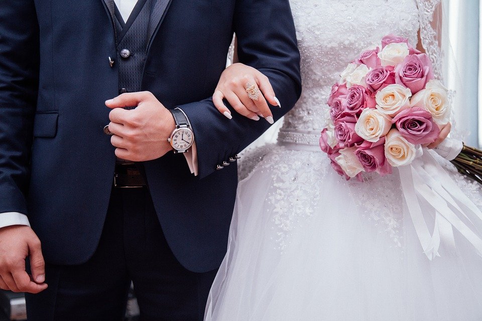 Mann und Frau in Hochzeitskleidung mit verschränkten Armen. | Quelle: Pixabay