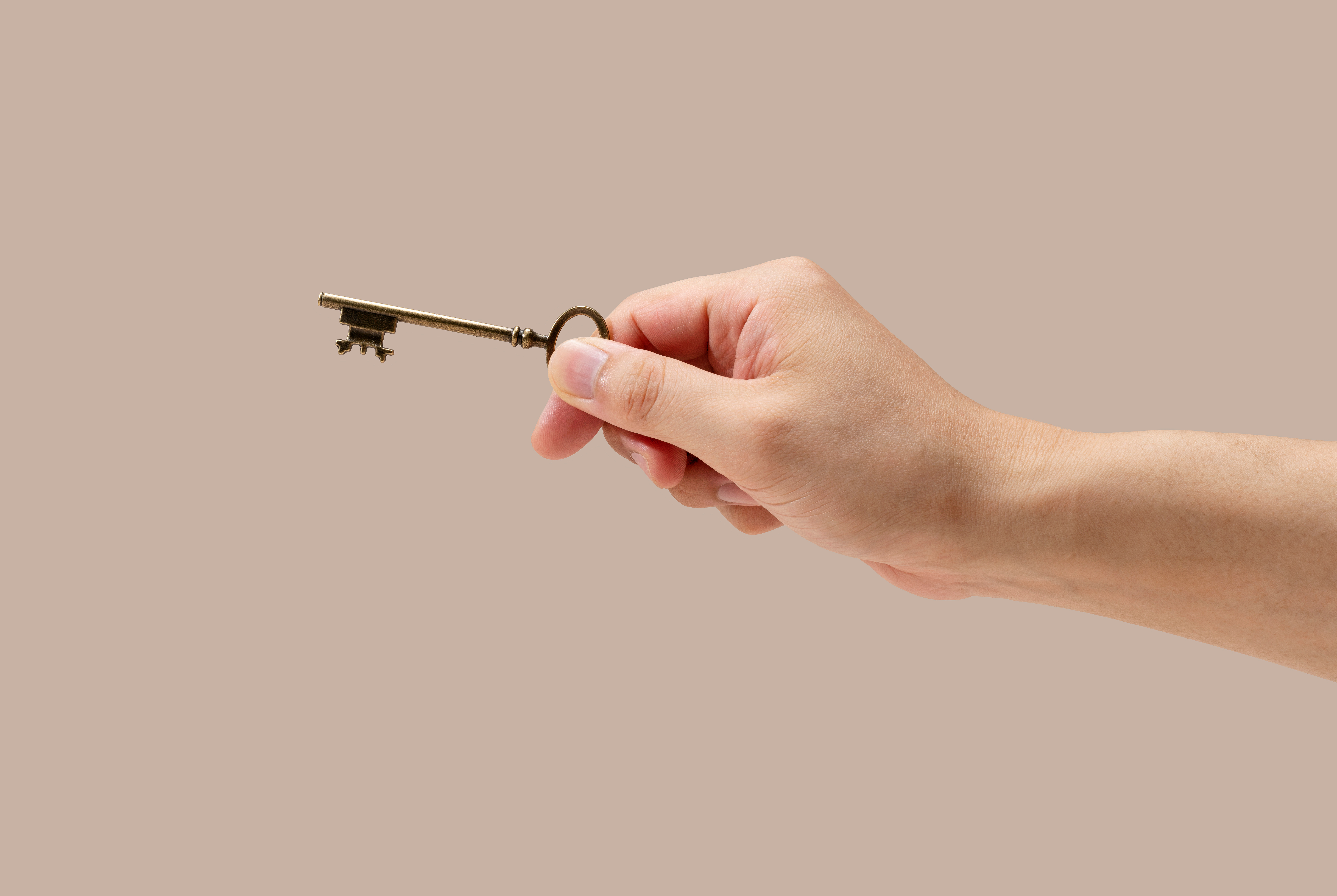 A man's hand holding a brass key | Source: Shutterstock