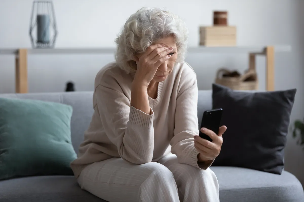 An unhappy senior woman looking at her phone screen | Source: Shutterstock