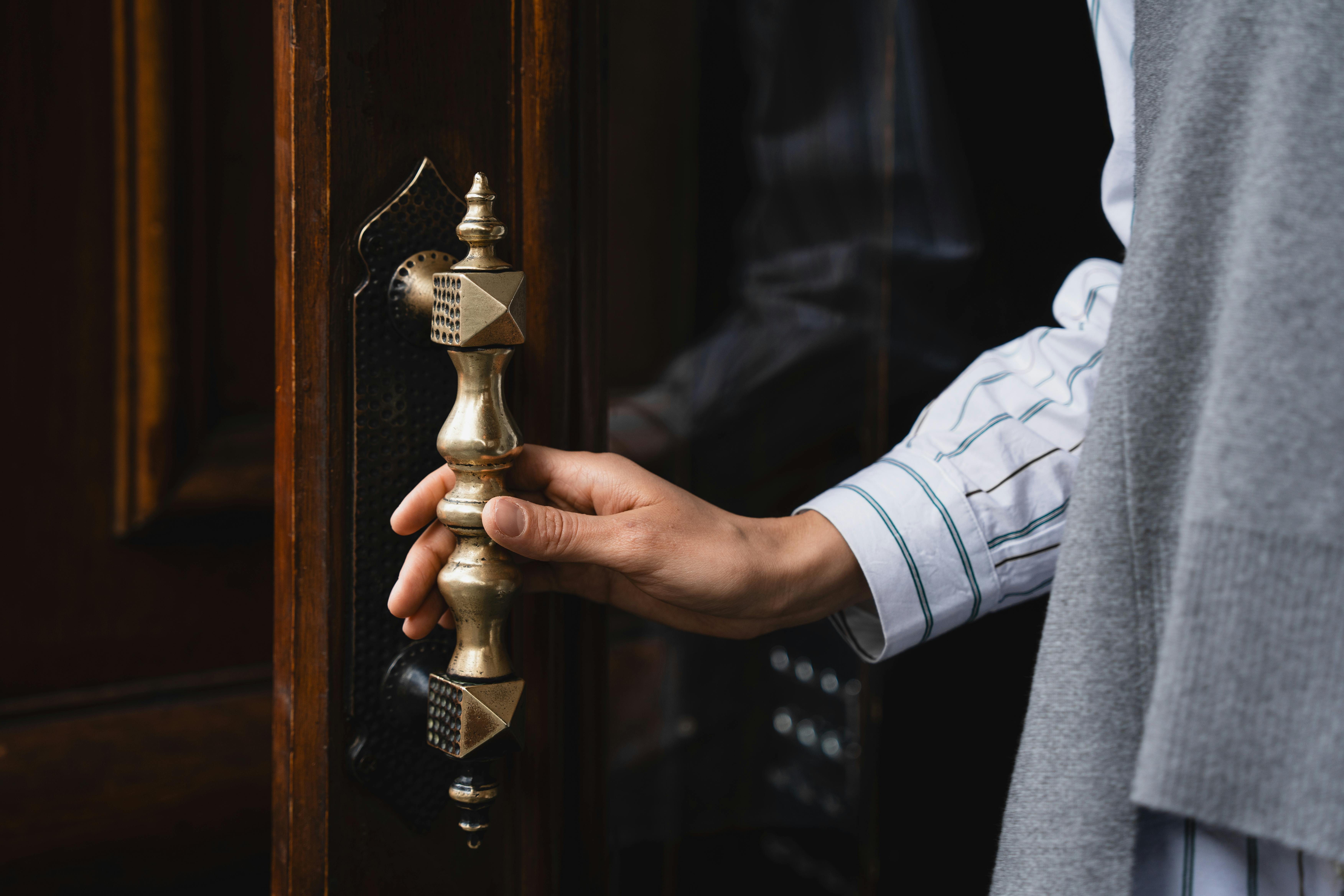 A hand grips a door handle, highlighting one of the most frequently touched and overlooked sources of household bacteria. | Source: Pexels