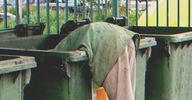 A person digging through a garbage bin | Source: Shutterstock